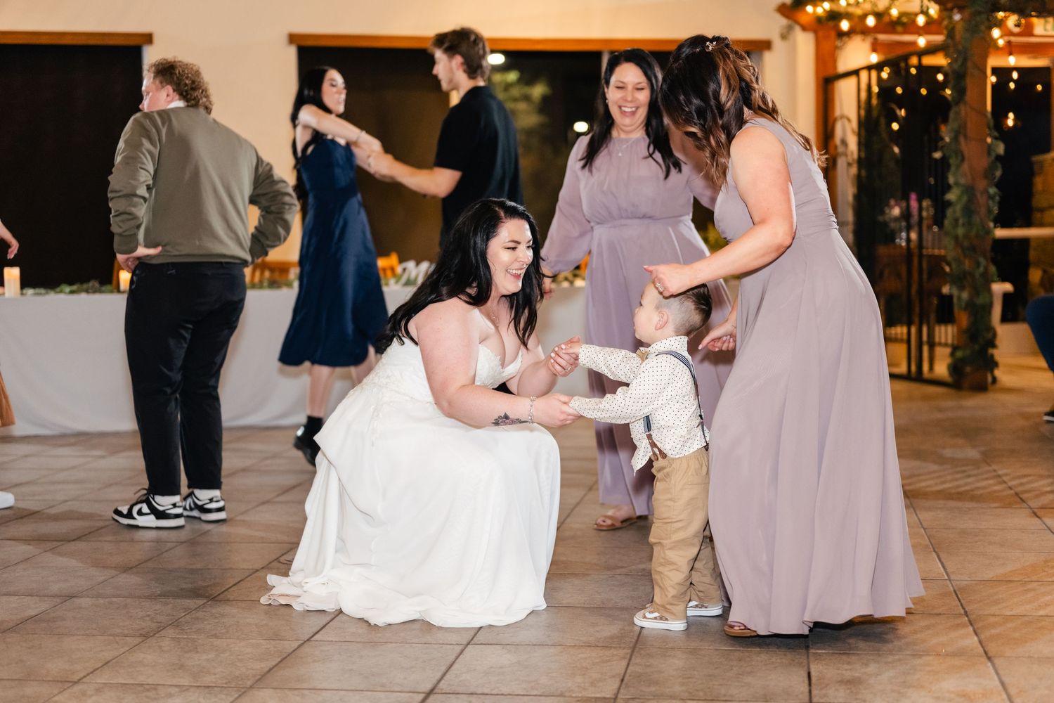 A young guest interacts with wedding attendees on the reception dance floor.