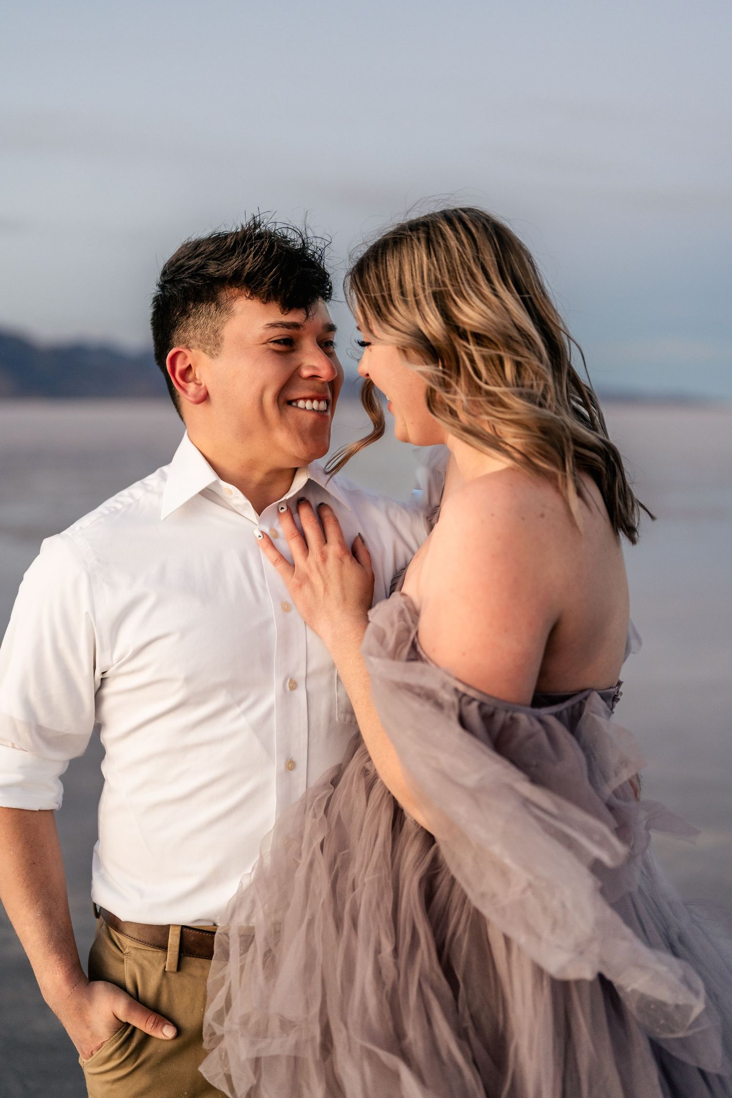 A couple laughs together amidst the serene beauty of the flooded Salt Flats during blue hour