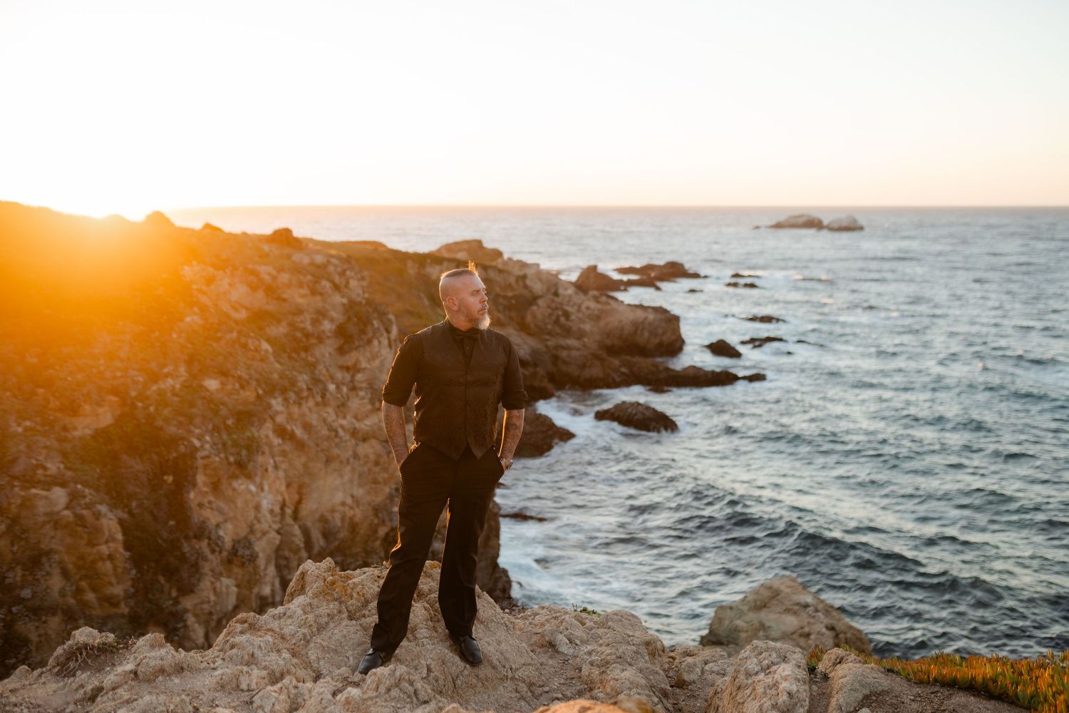 A stunning coastal sunset view with rocky cliffs and crashing waves along the Pacific Ocean shoreline.