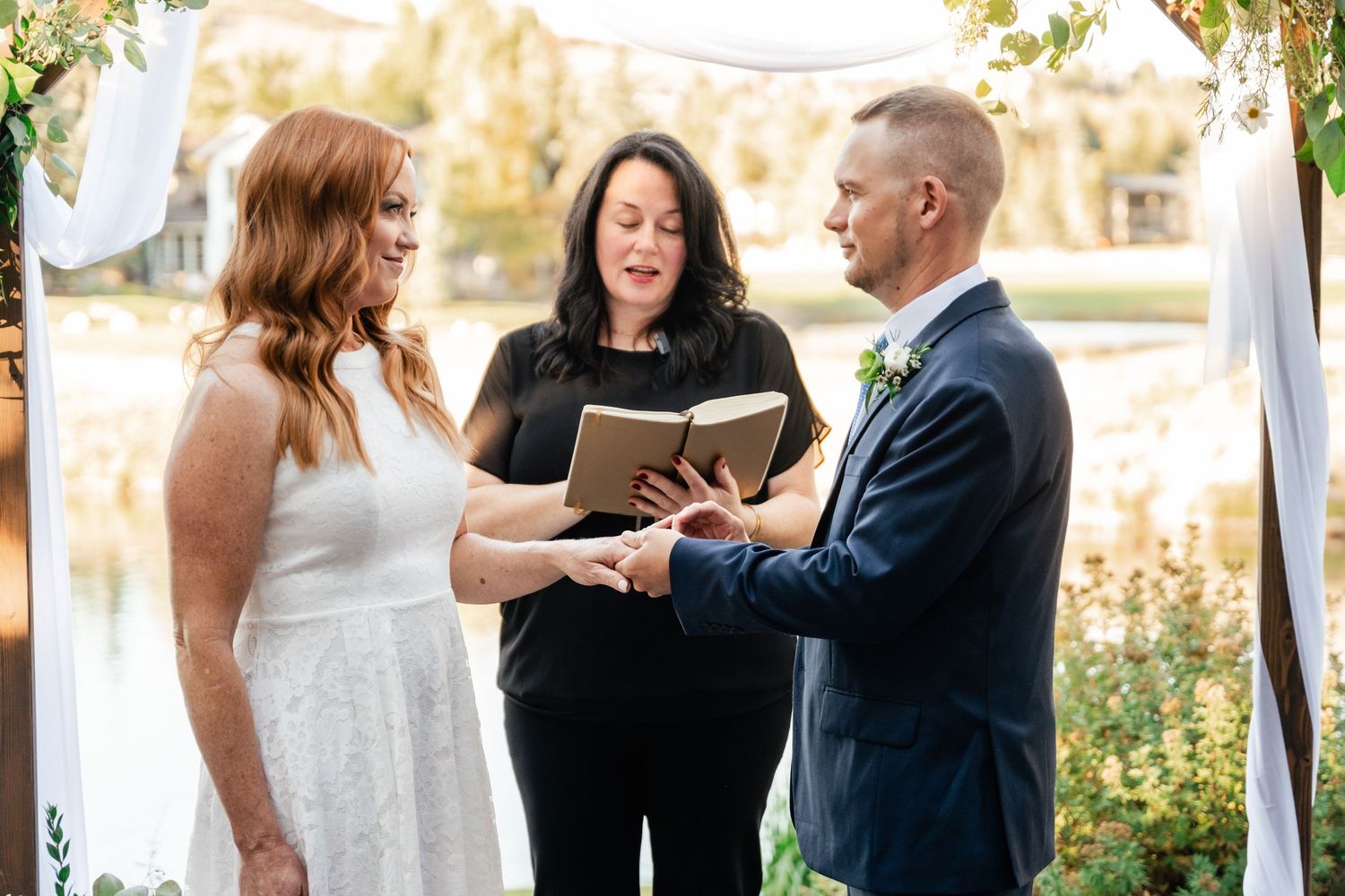 Intimate outdoor wedding ceremony taking place on a wooden deck with water views.