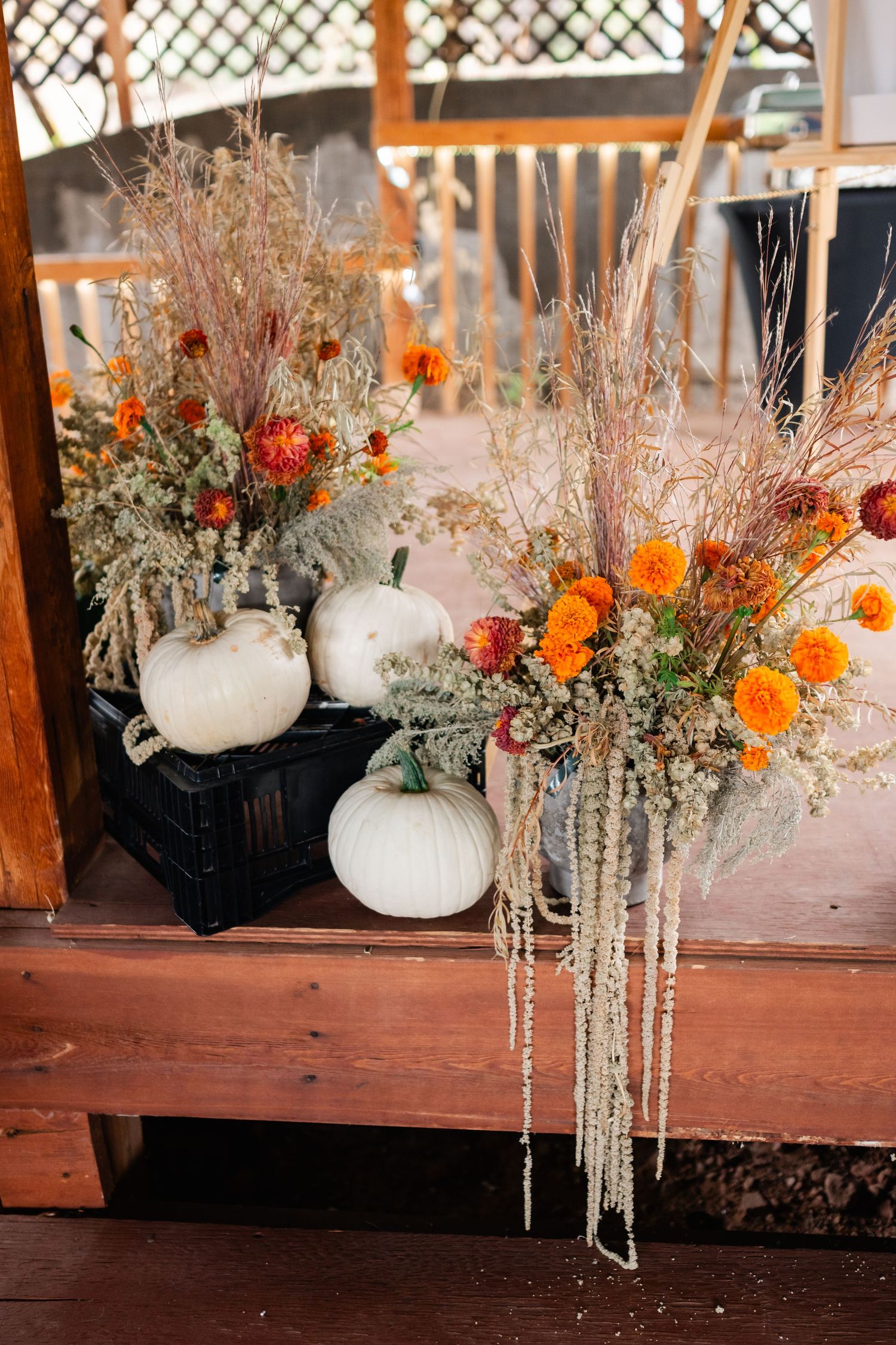 White pumpkins decorated with dried flowers and orange marigolds create an elegant autumn centerpiece display.