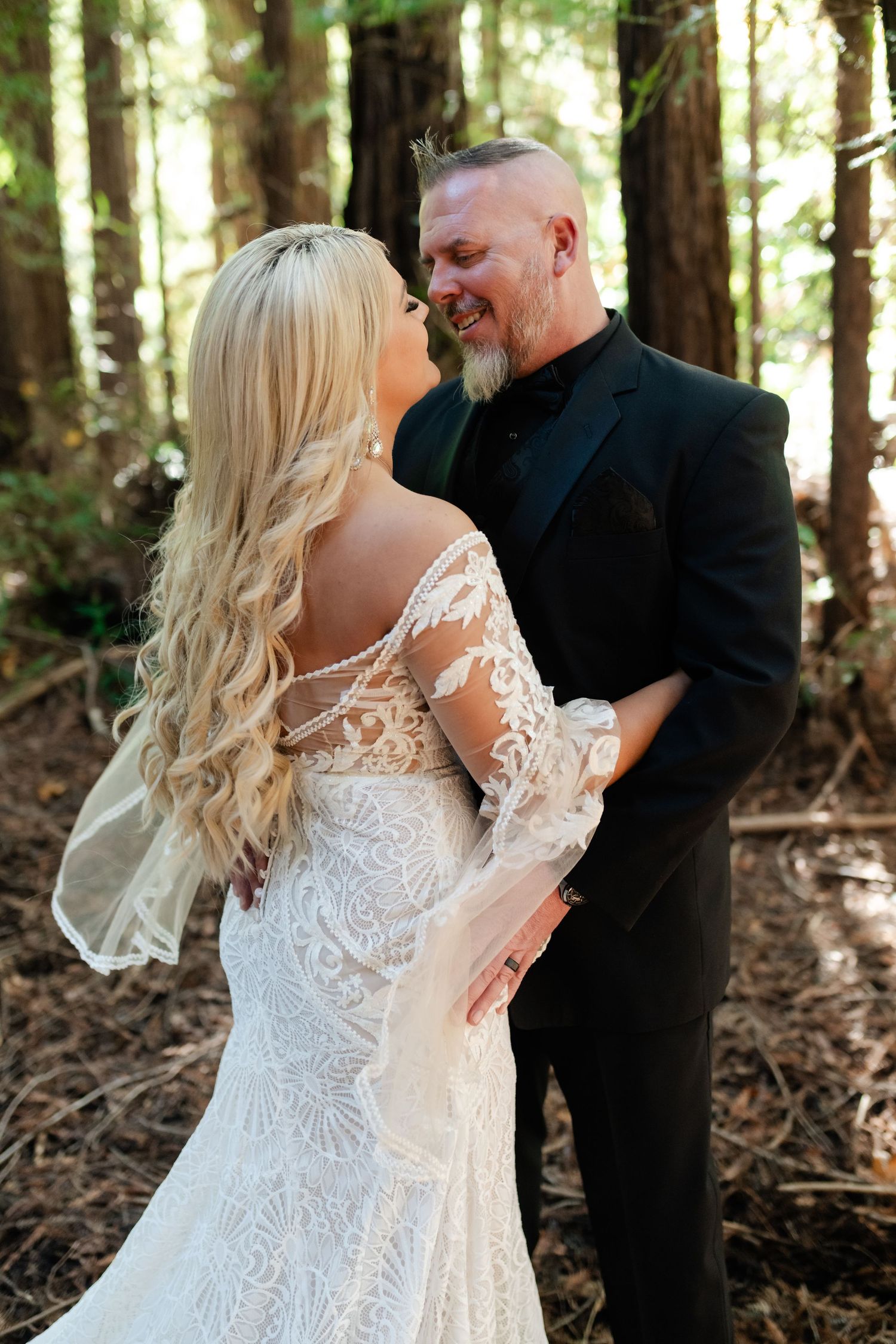 Romantic wedding couple shares intimate moments in a sunlit redwood forest setting.