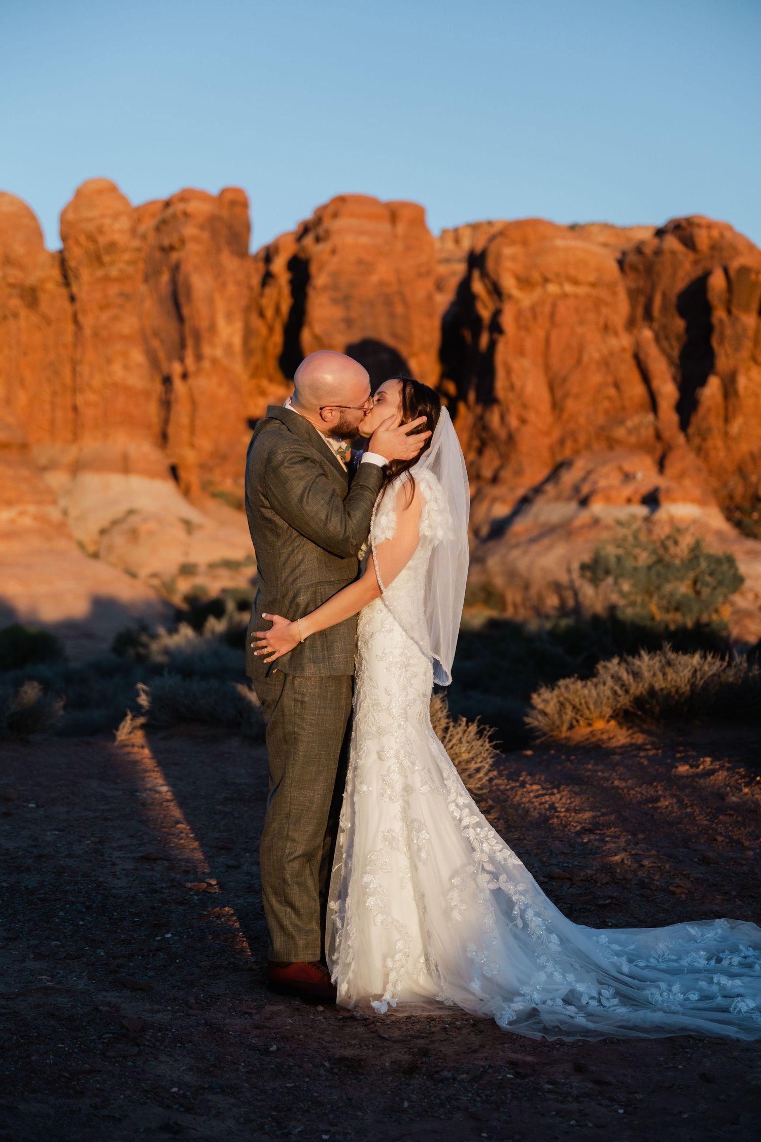 A wedding couple embraces during sunset with majestic red rock formations in the background.