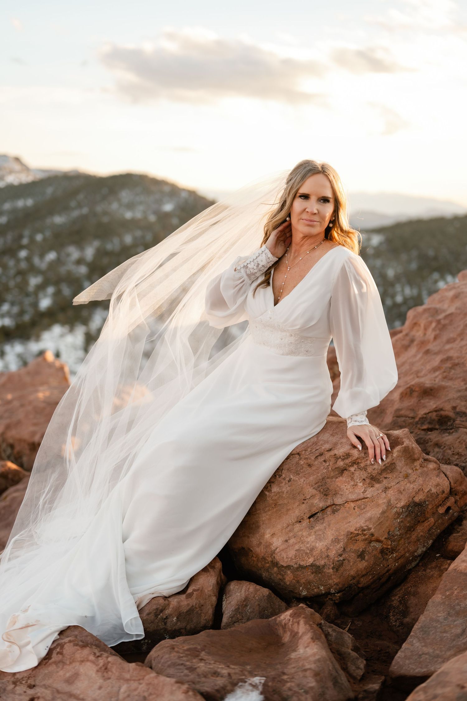 Flowing white wedding dress contrasts against red rocks during a bridal photoshoot.