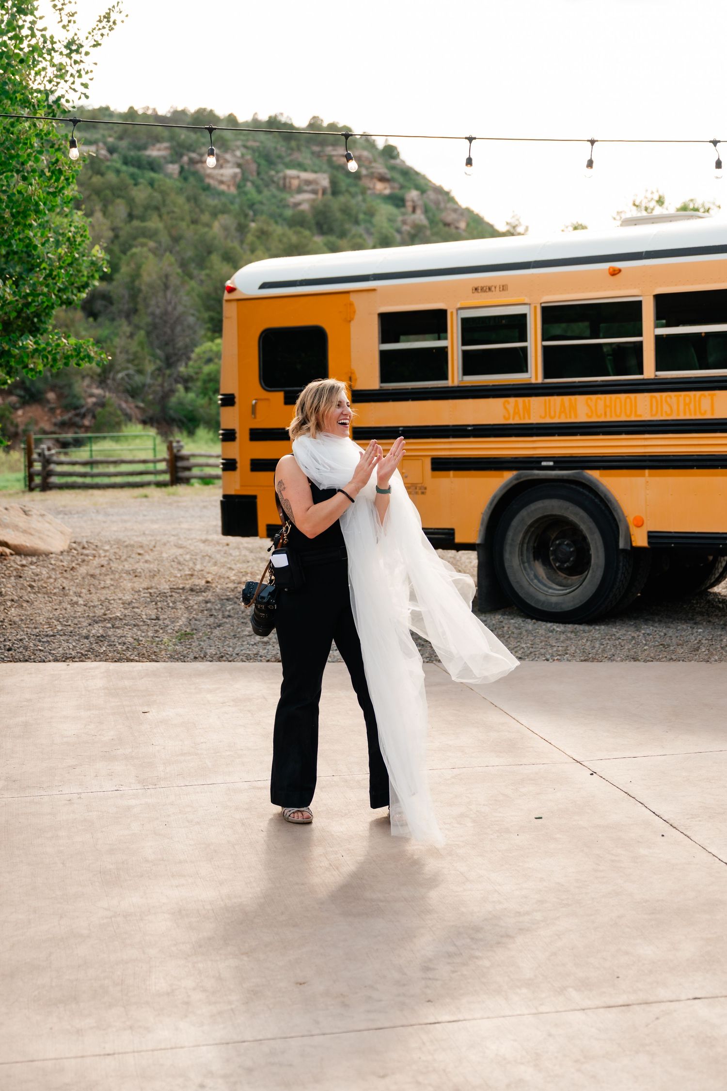 A yellow school bus parked outside a mountain wedding venue at sunset.