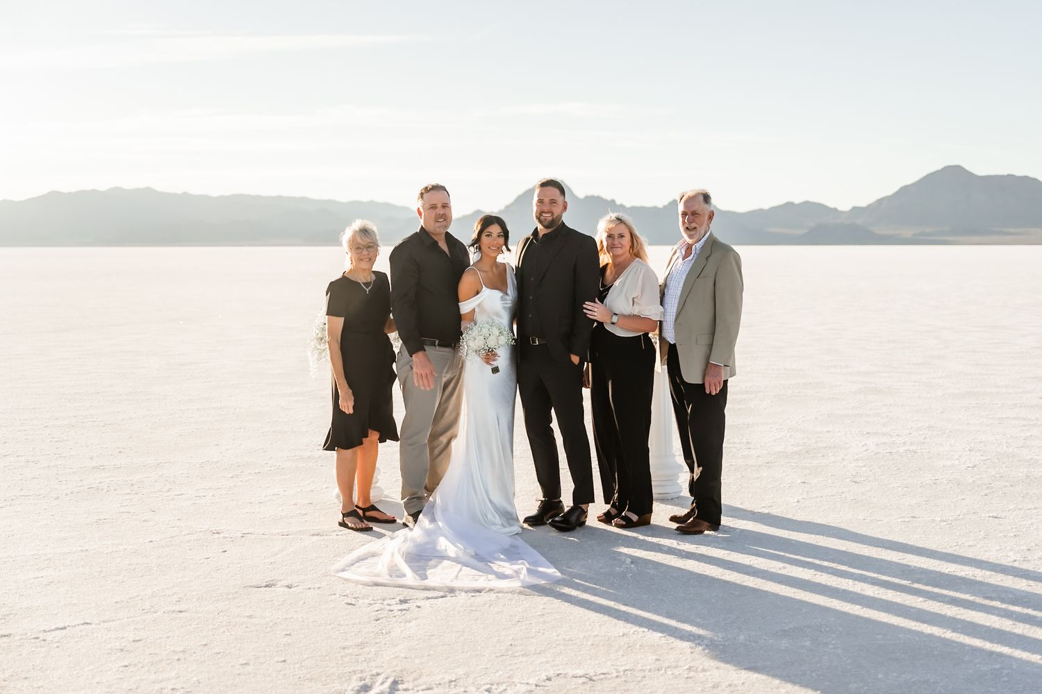 Wide angle shot of wedding party and guests gathered on bright white salt flats.