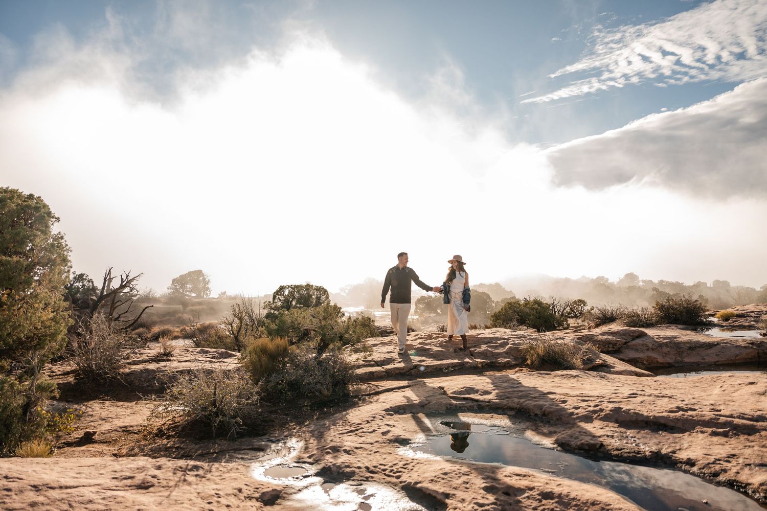 Silhouettes walking together through desert terrain with dramatic cloudy skies overhead.