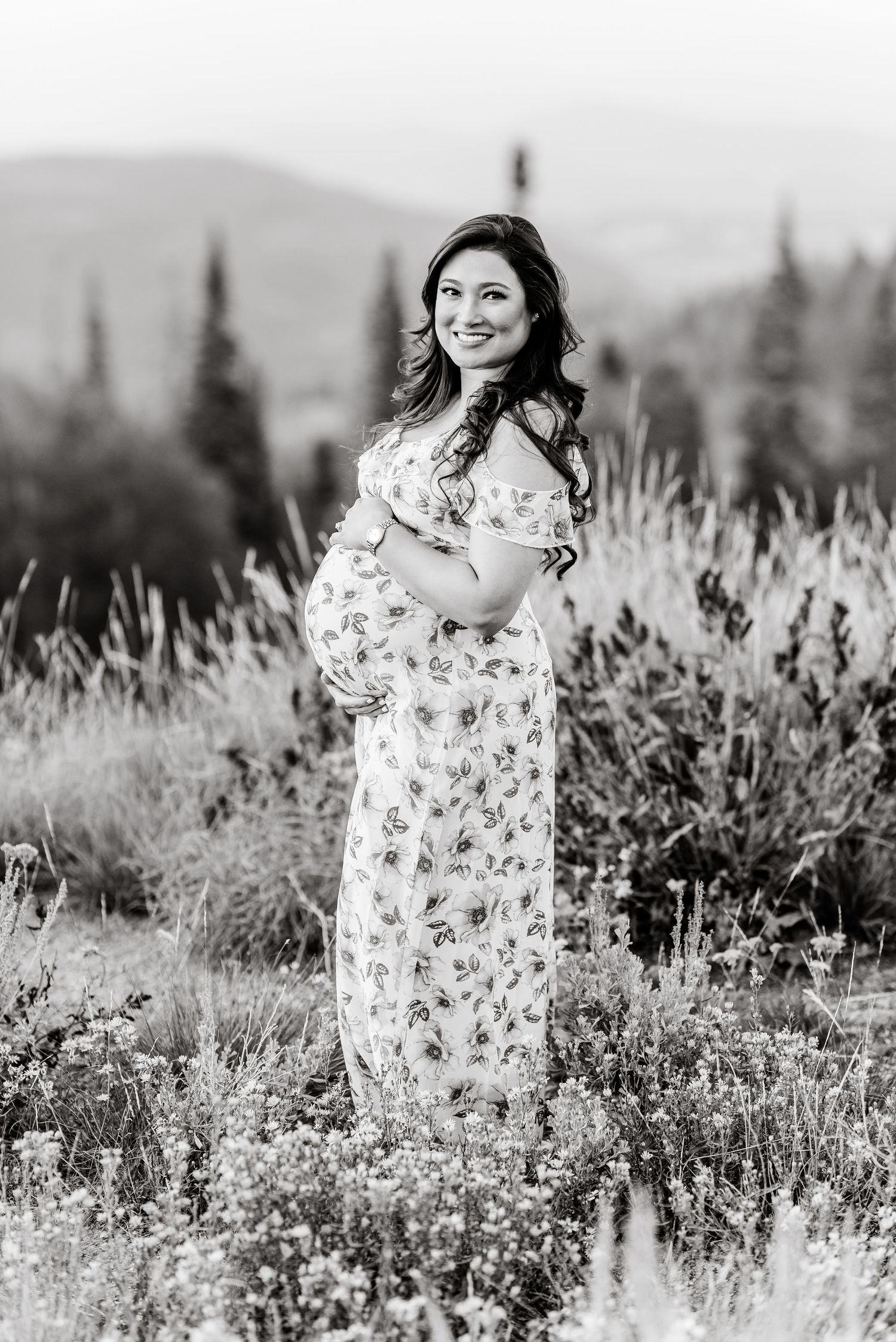 Black and white photo series of a person in a floral dress standing in a wildflower meadow with mountains in background.