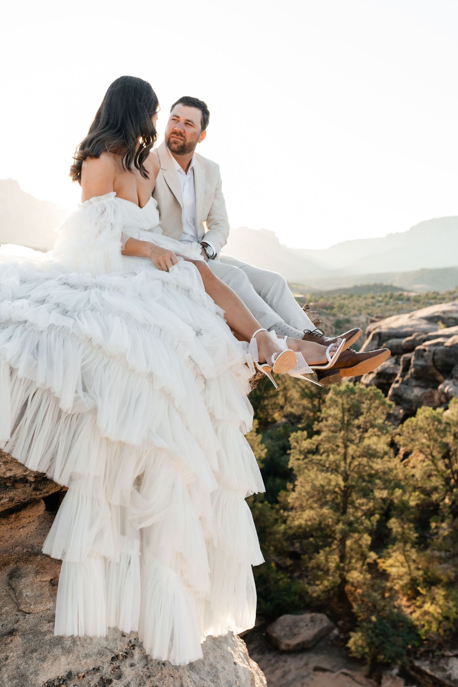 Zion Adventure Session. Wedding couple shares romantic moments on desert cliffs during golden hour.