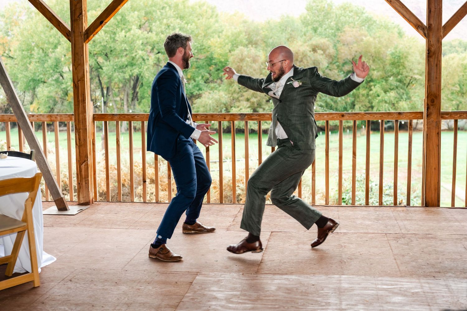 Two people dancing energetically and having fun on a covered outdoor wooden deck.