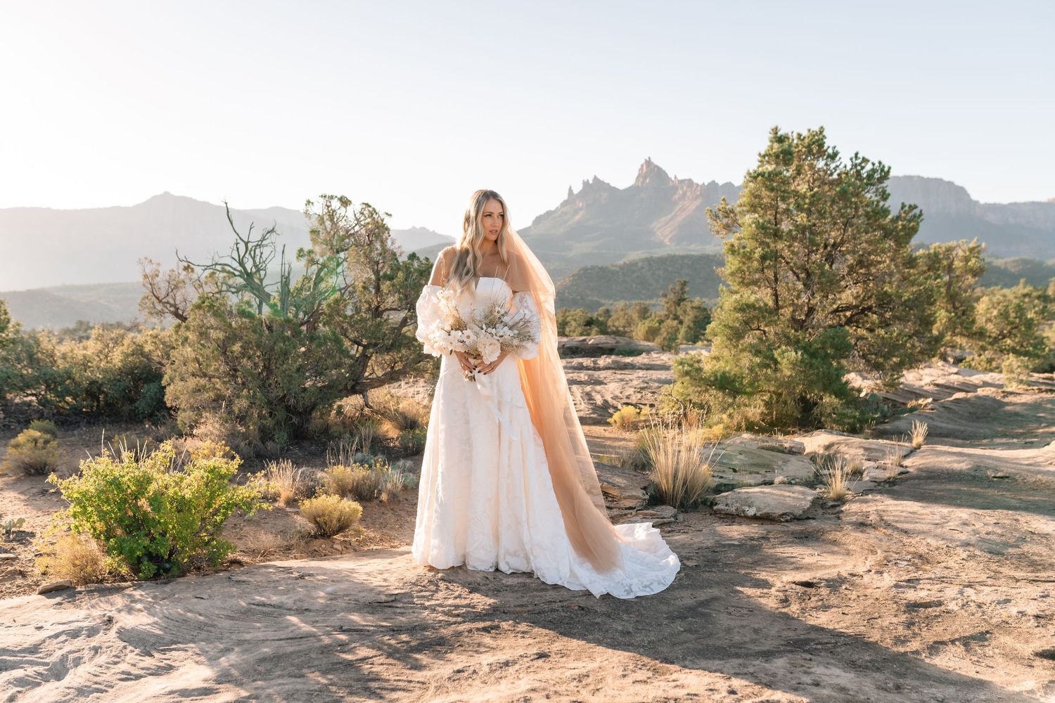 Zions wedding photographer takes beautiful desert sunrise bridals featuring a unique veil and dried floral bouquet.