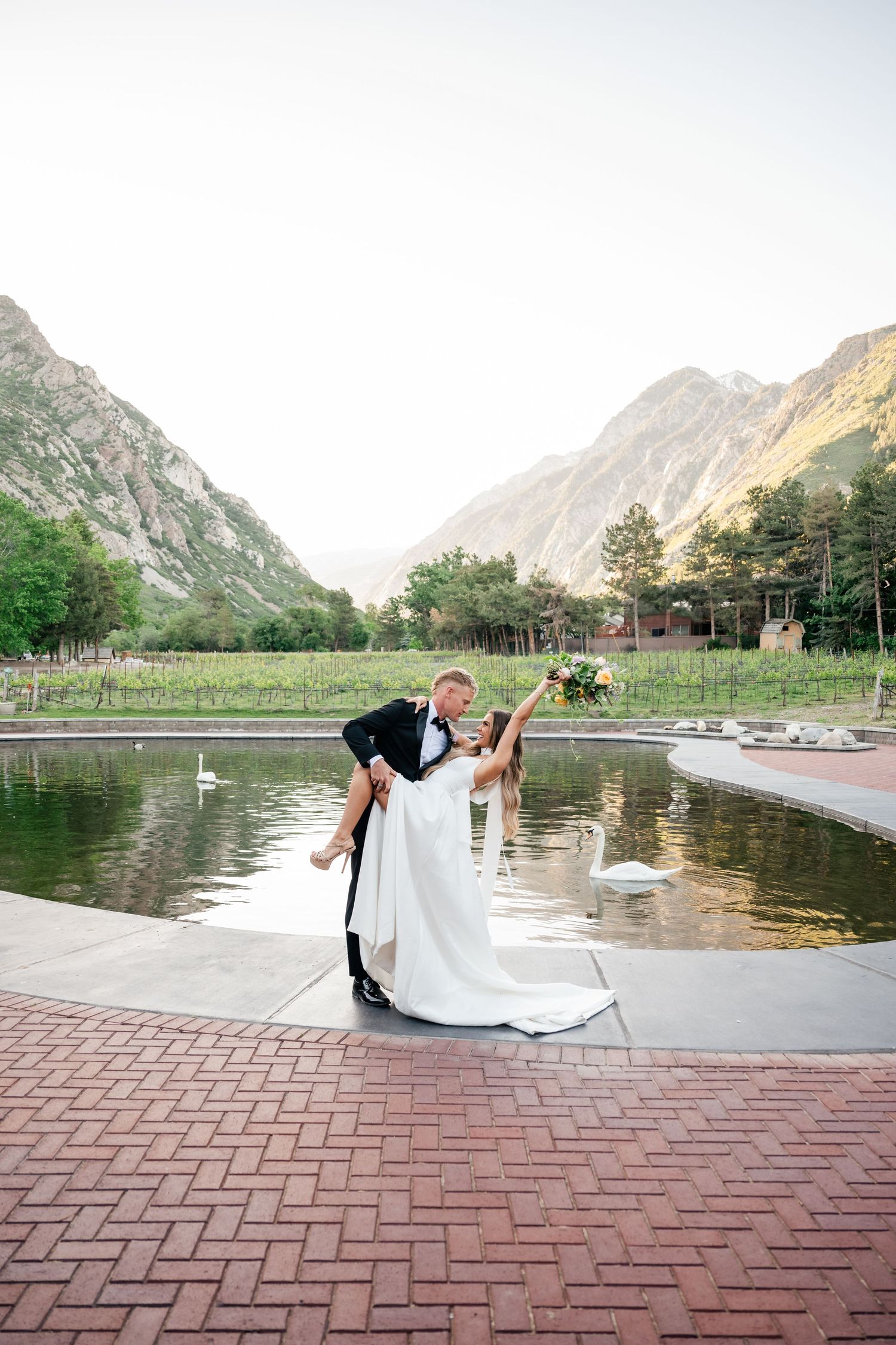 Romantic mountain lake scene with couple dancing on brick patio surrounded by dramatic peaks.