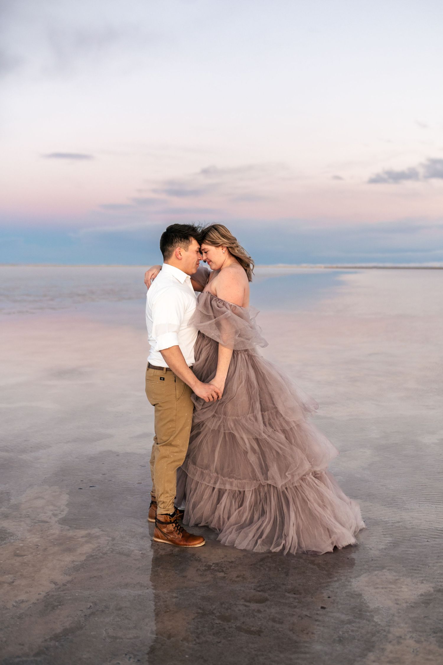 A tender embrace between the couple, illuminated by the soft blue light of blue hour at the Salt Flats.