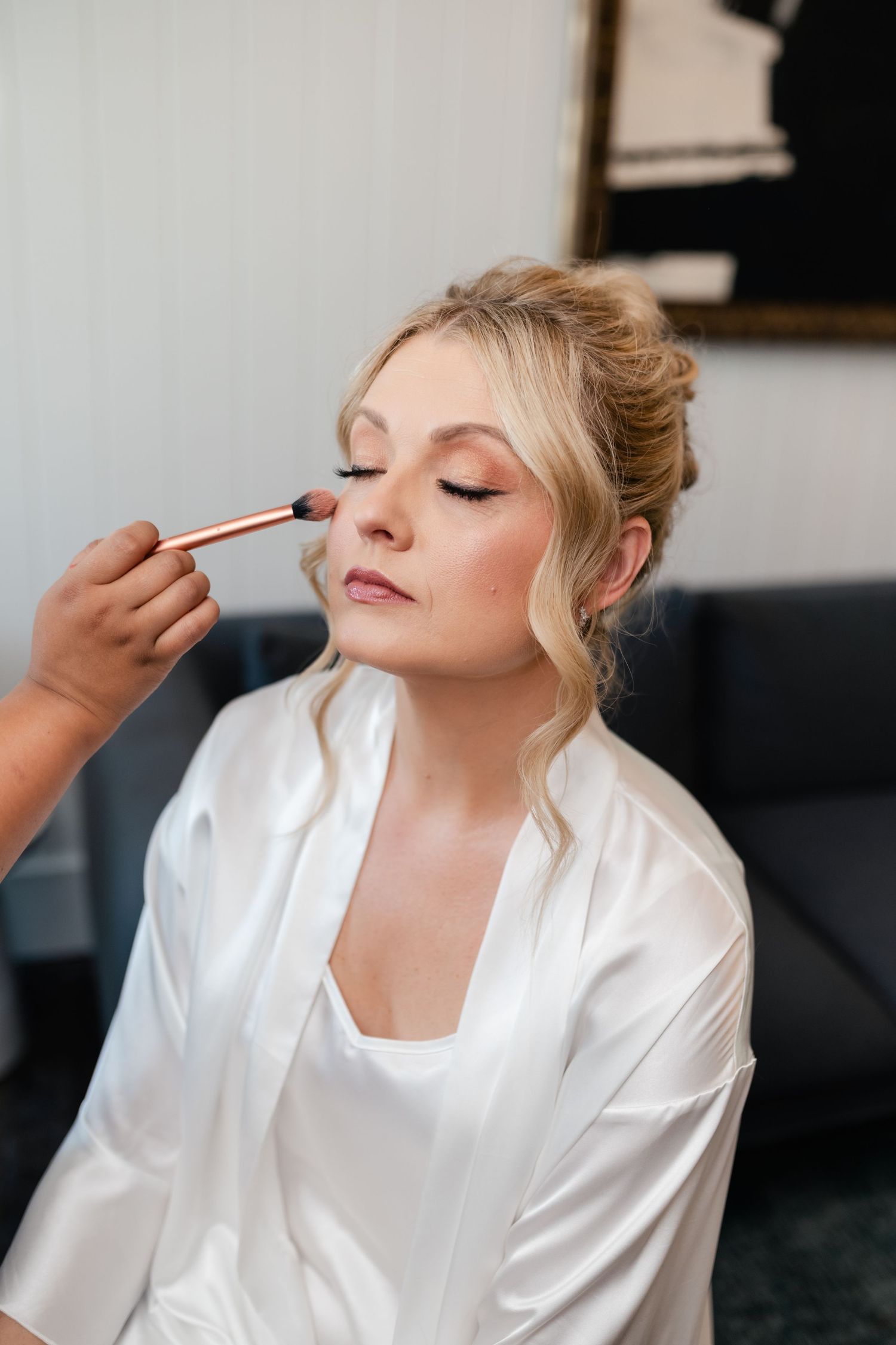 Makeup artist applying eyeshadow during bridal preparation.