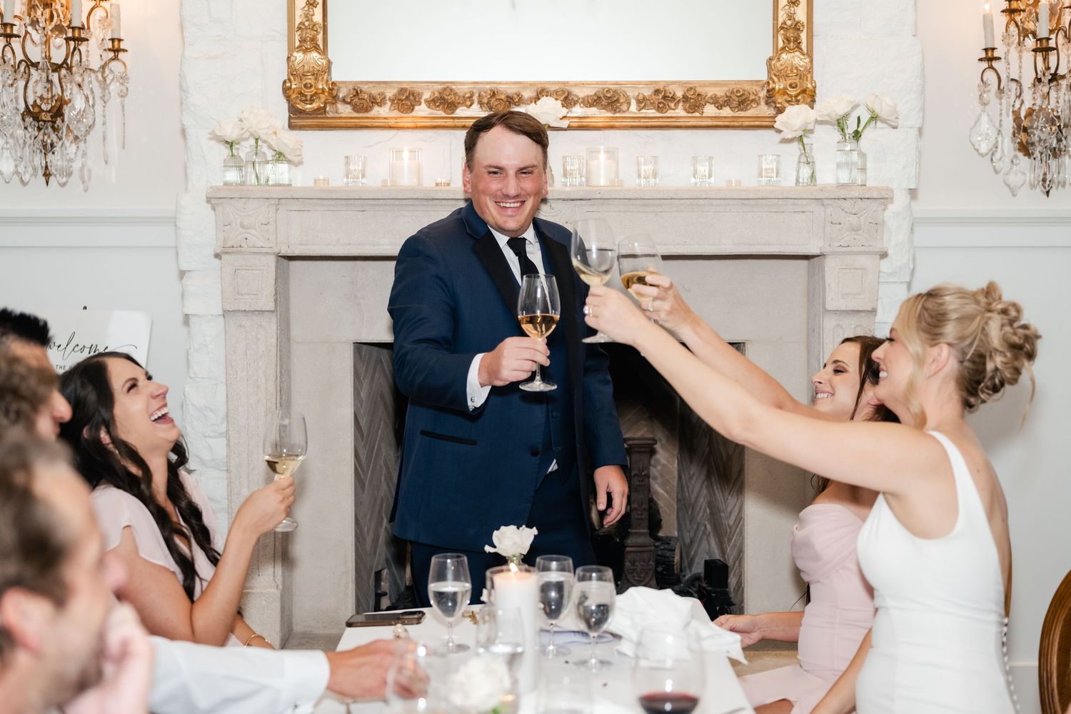 Guests raise their glasses in a celebratory toast at an elegant reception with ornate decor.