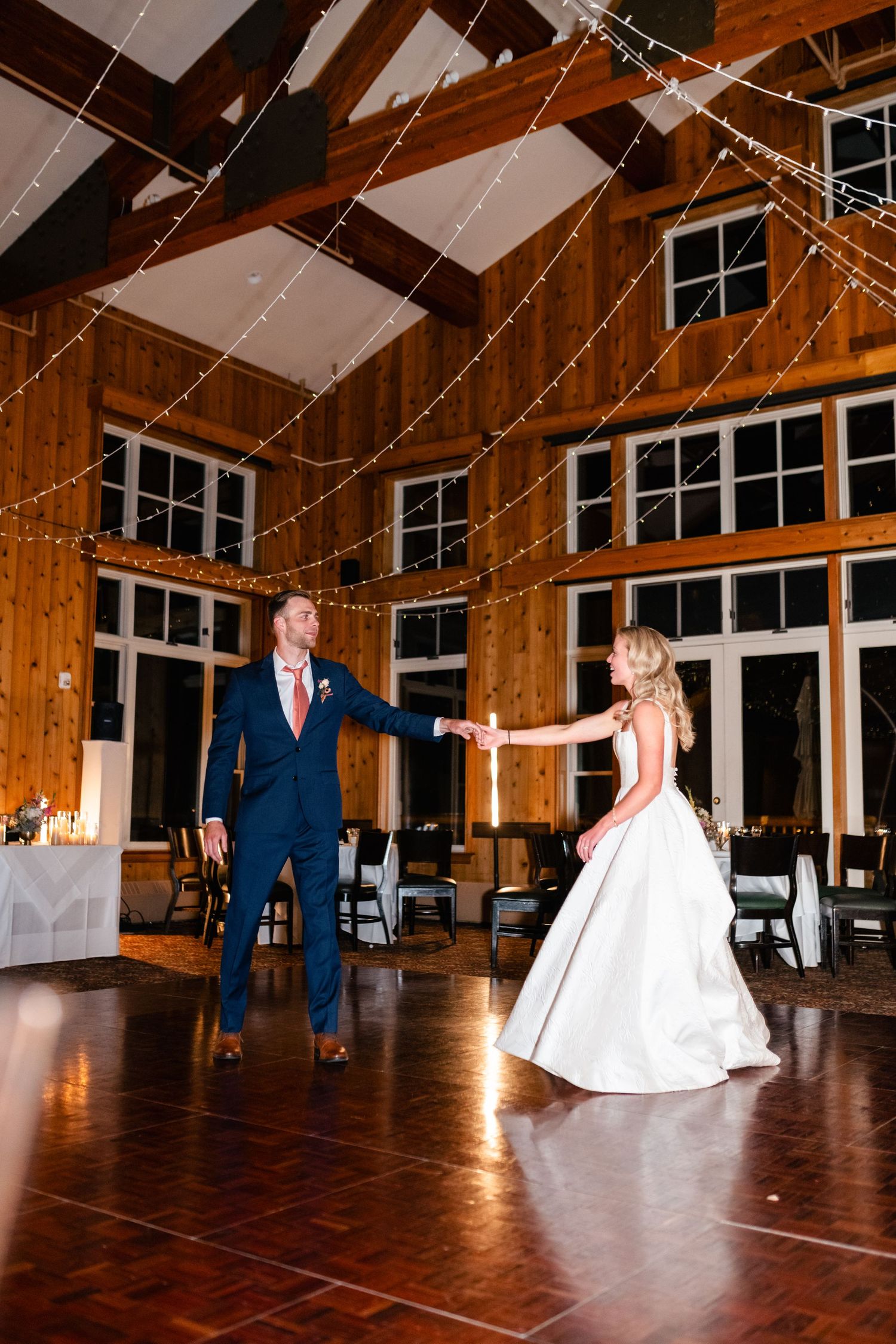 Newlyweds perform a choreographed dance in a rustic wooden reception venue.
