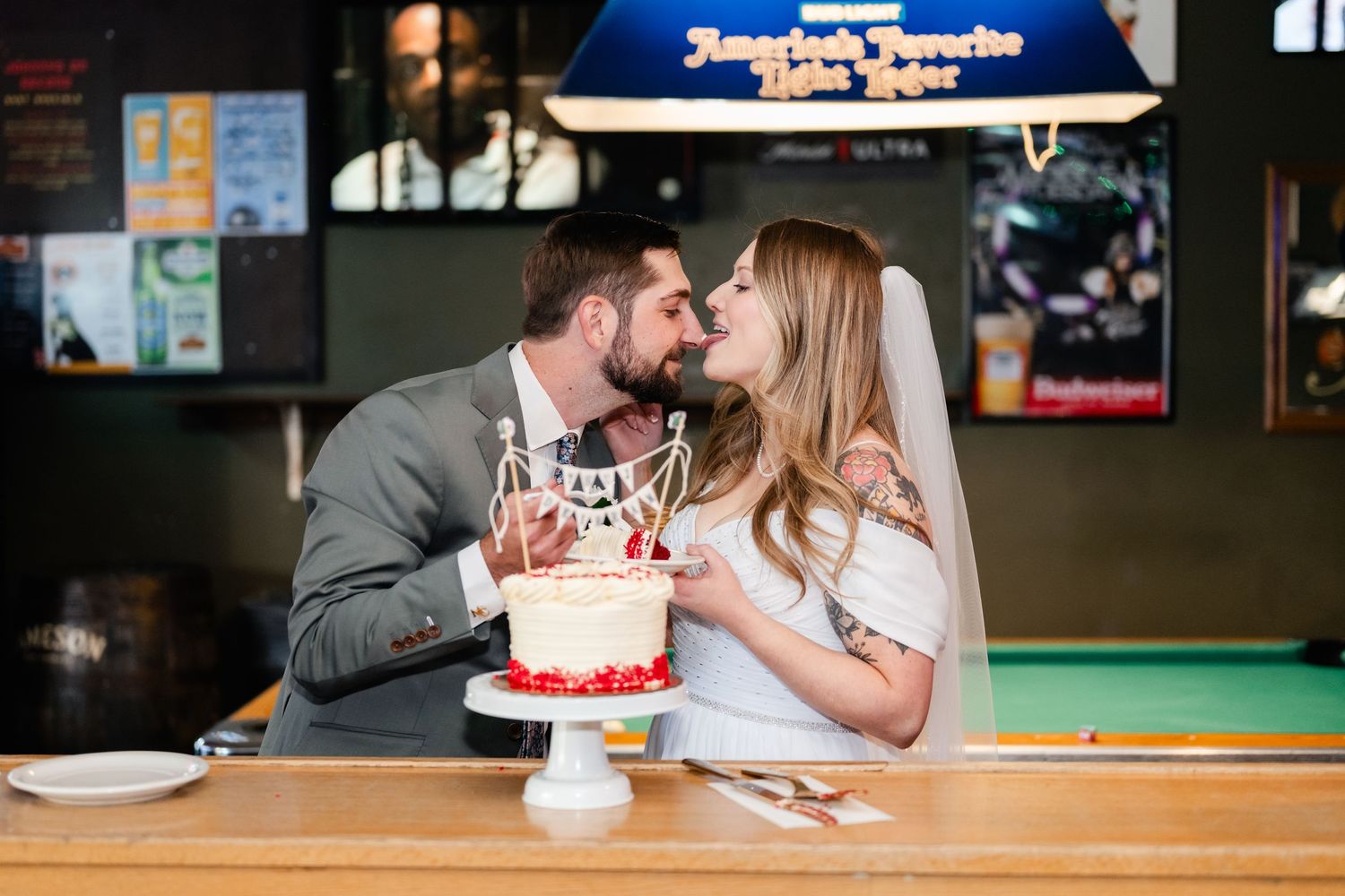 A couple enjoys cake together at a casual bar celebration.