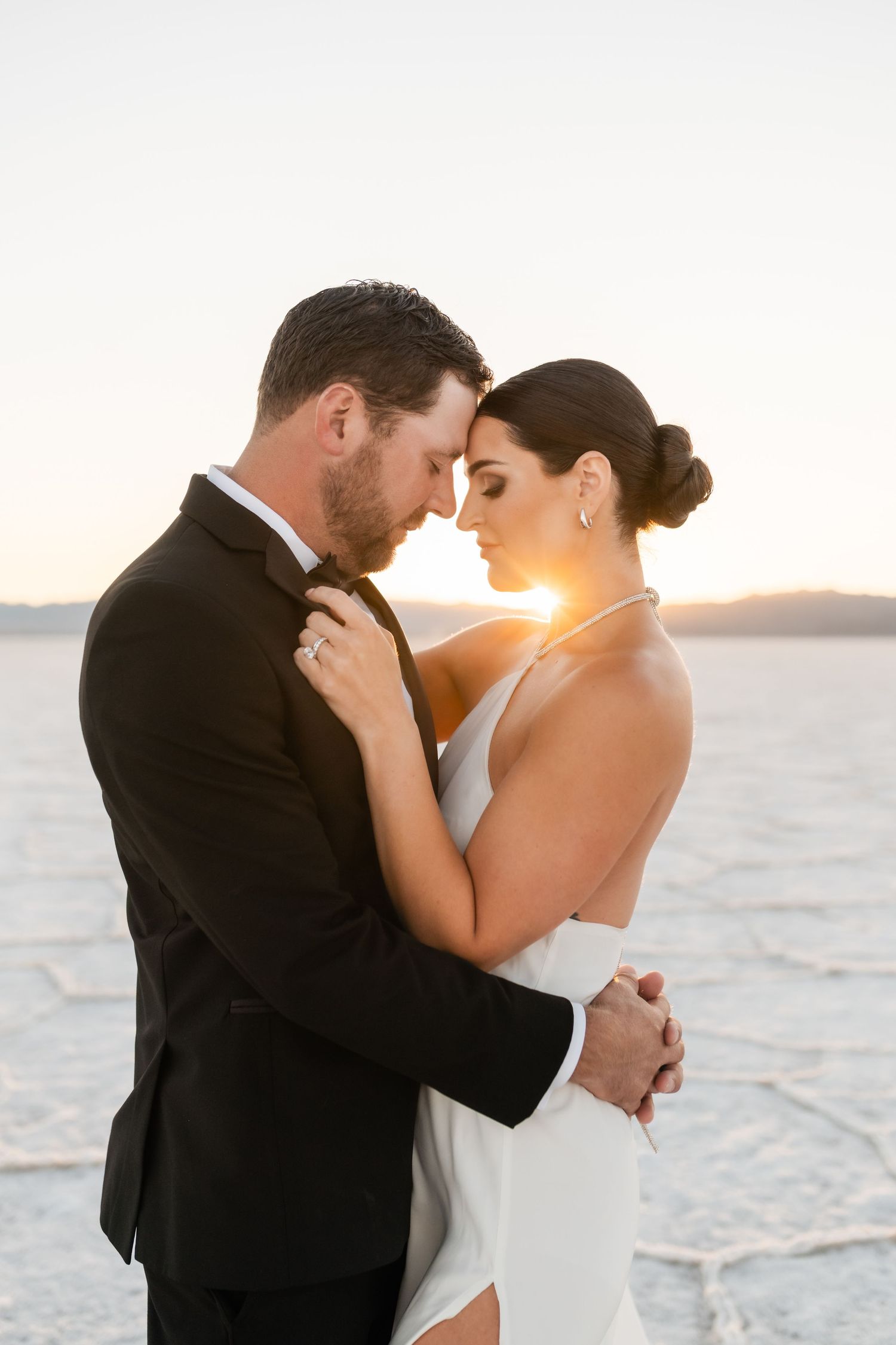 Utah Salt Flats Photographer. A romantic couple embraces on the salt flats during golden hour.