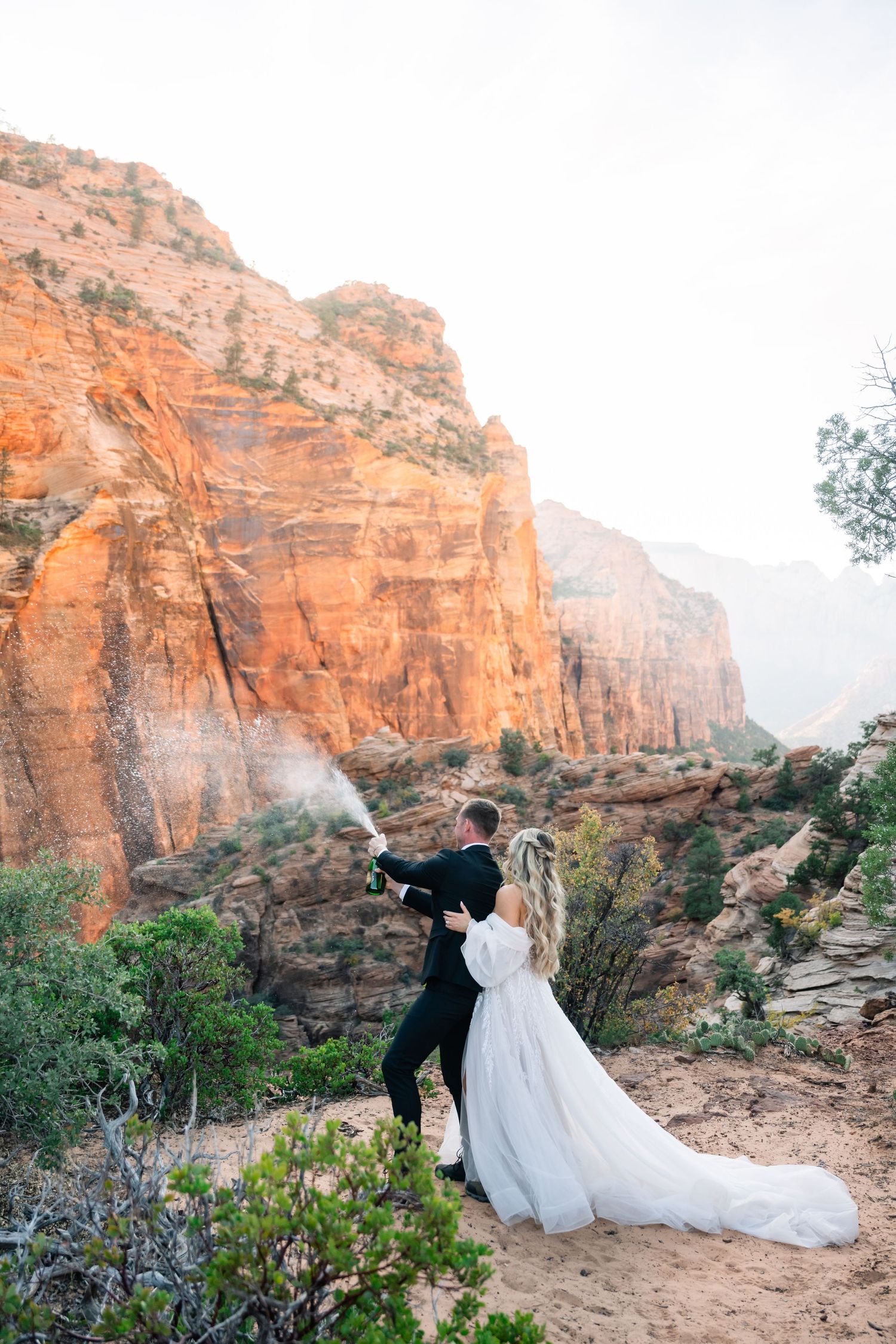 A couple creates a celebratory moment against majestic red rock canyon walls.