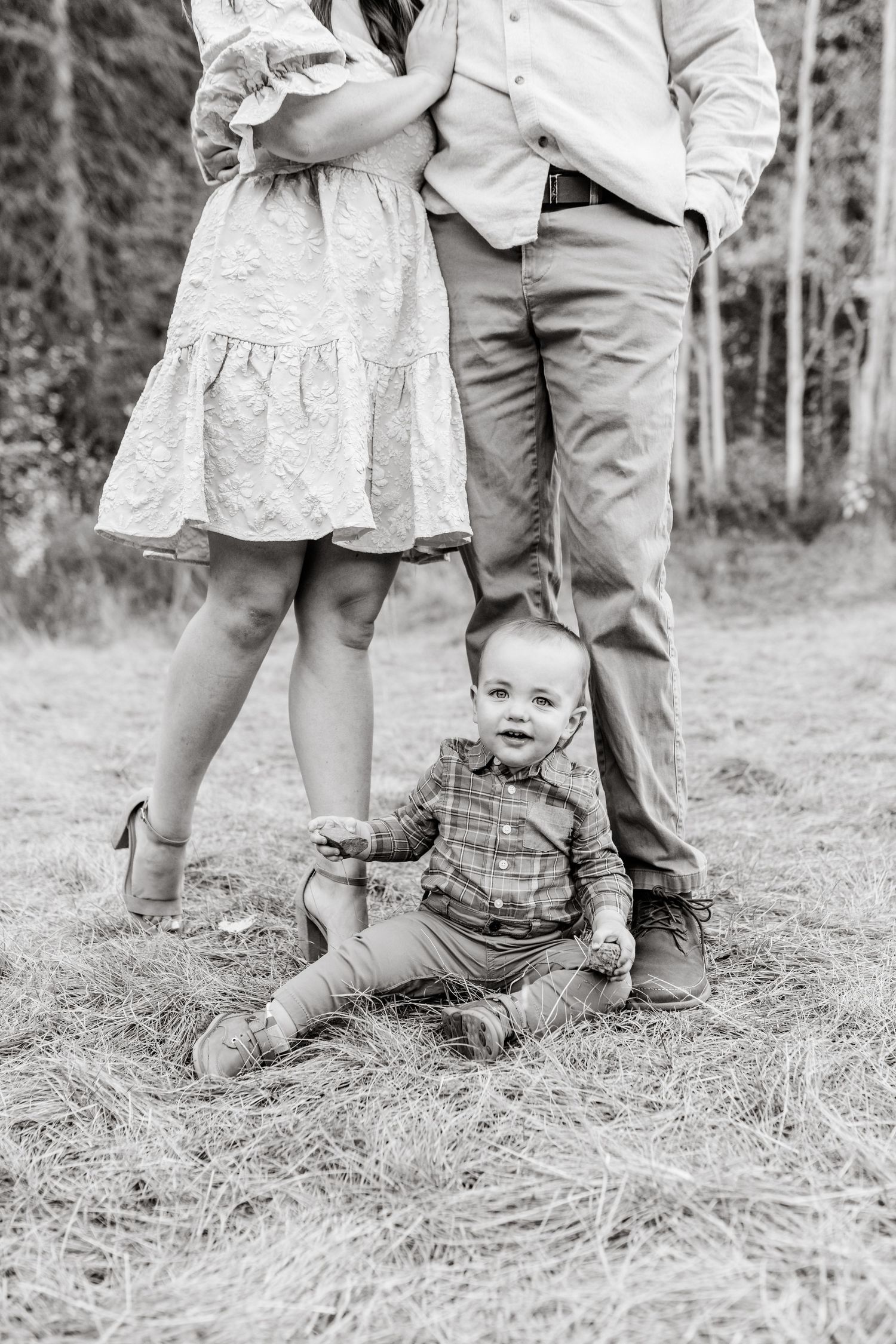 baby boy sitting at parents feet during their fall family session captured by Utah Family Photographer.