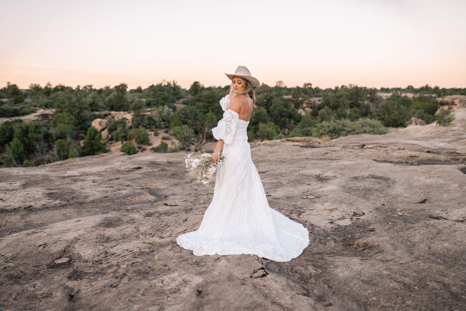 Bridal portrait with bohemian dried flower bouquet and western hat at sunset.
