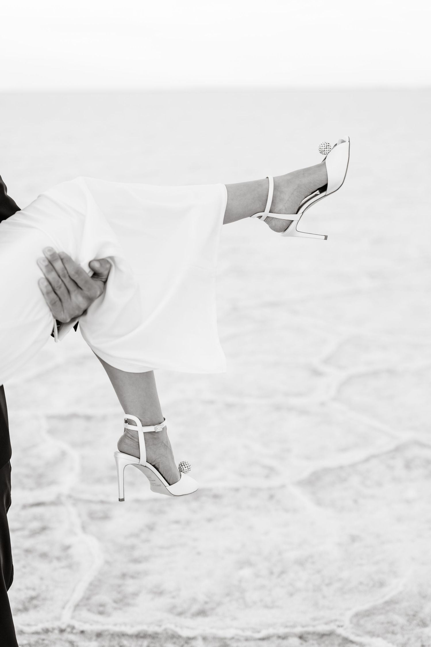 Salt Flats Elopement Photographer. Close-up of elegant white bridal shoes against the textured surface of salt flats.