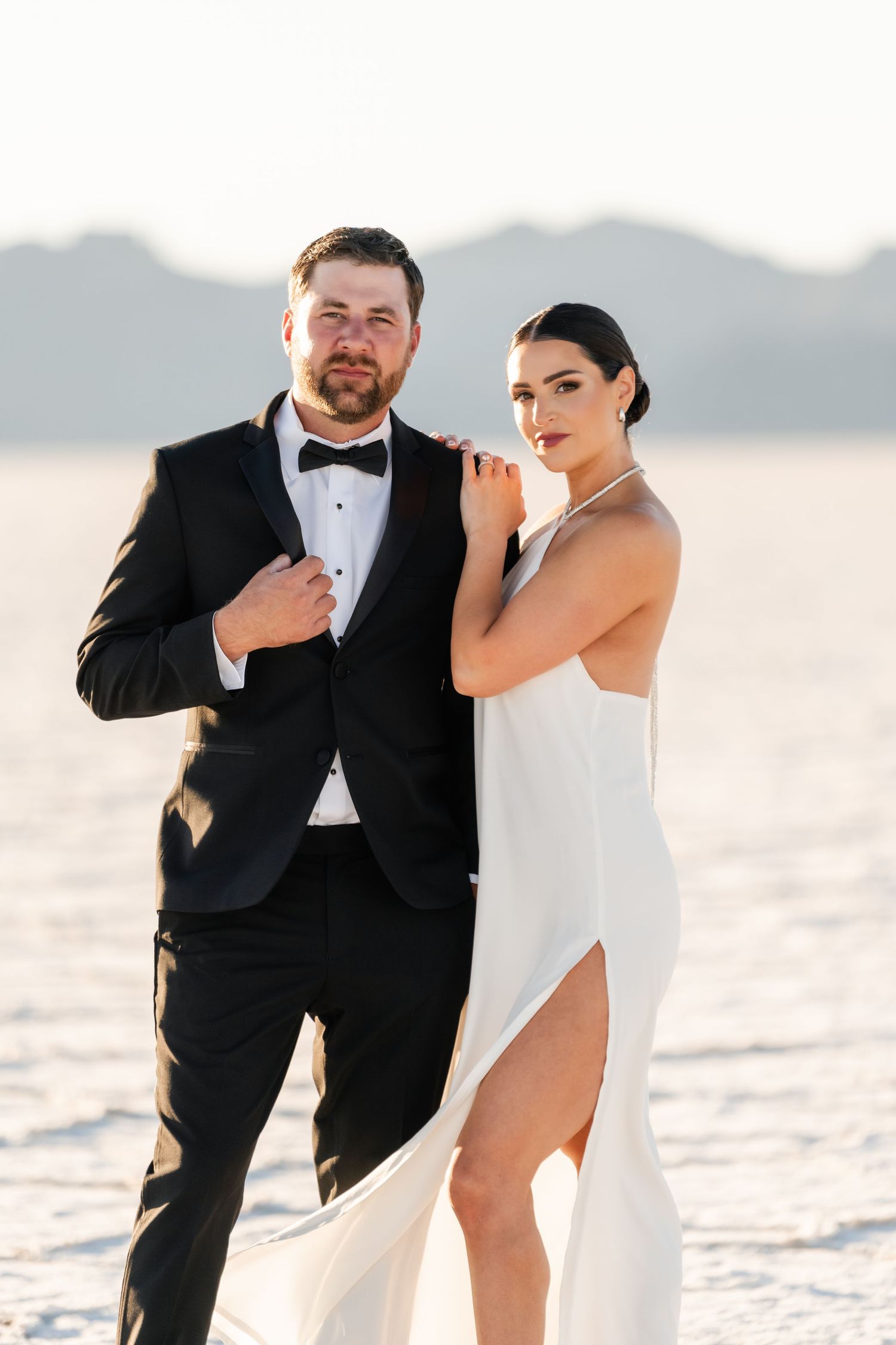 Salt Flats Photographer. A couple in contrasting black and white outfits poses playfully on salt flats at sunset.