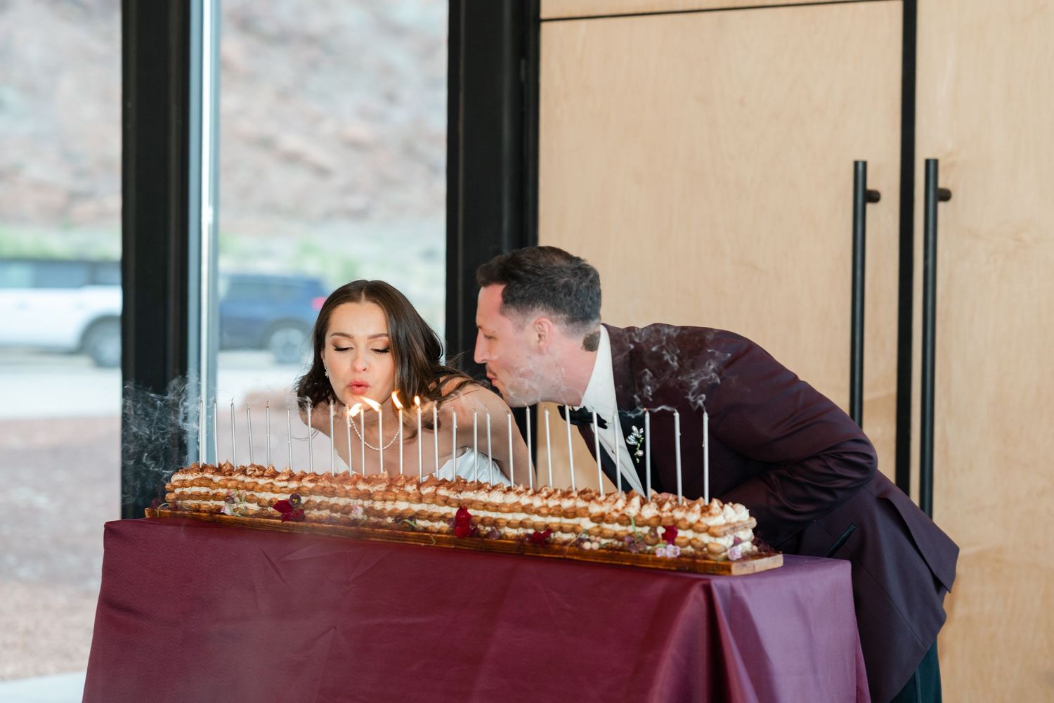 Couple blowing out candles on a dessert display at an elegant celebration event.