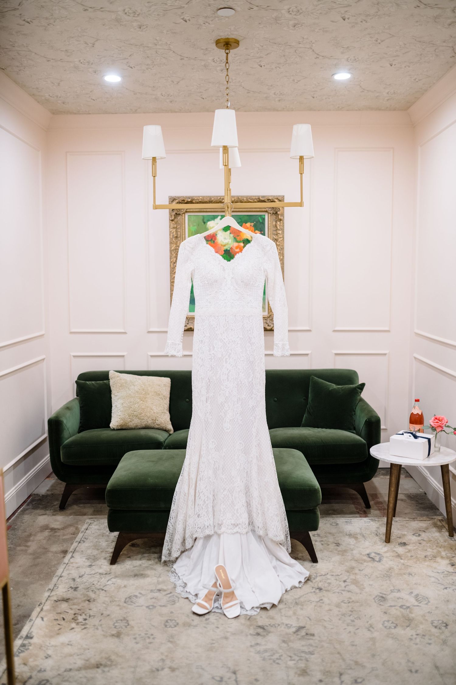 A series of wedding preparation photos showing a white bridal gown displayed against green velvet furniture in a modern room. The Wild Oak