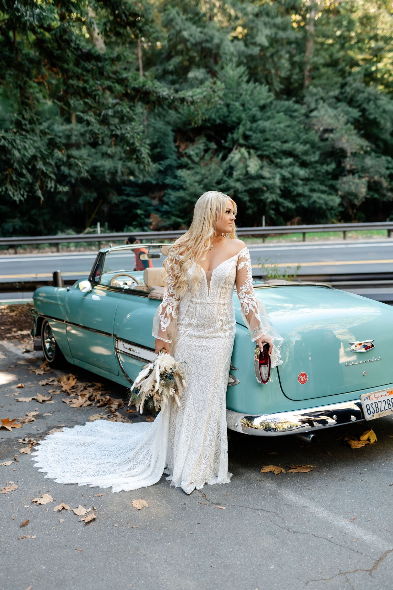 Vintage turquoise convertible car with white lace wedding dress draped over the side.