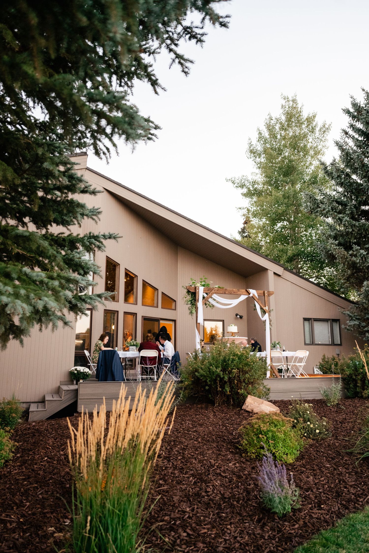 Evening view of a contemporary home with vaulted ceiling and outdoor event lighting visible through windows.