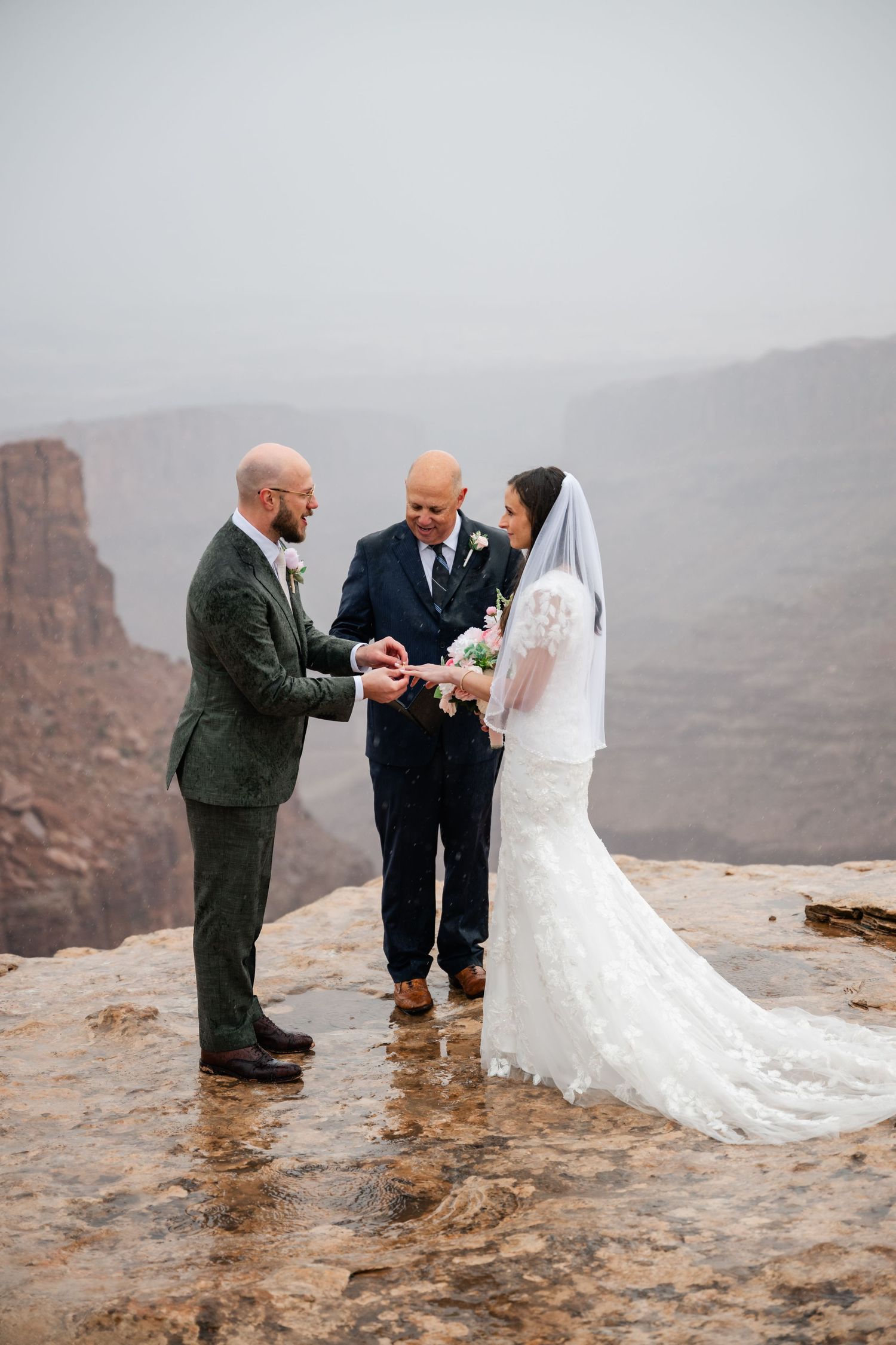 Intimate wedding ceremony taking place on dramatic cliff edge during overcast weather.