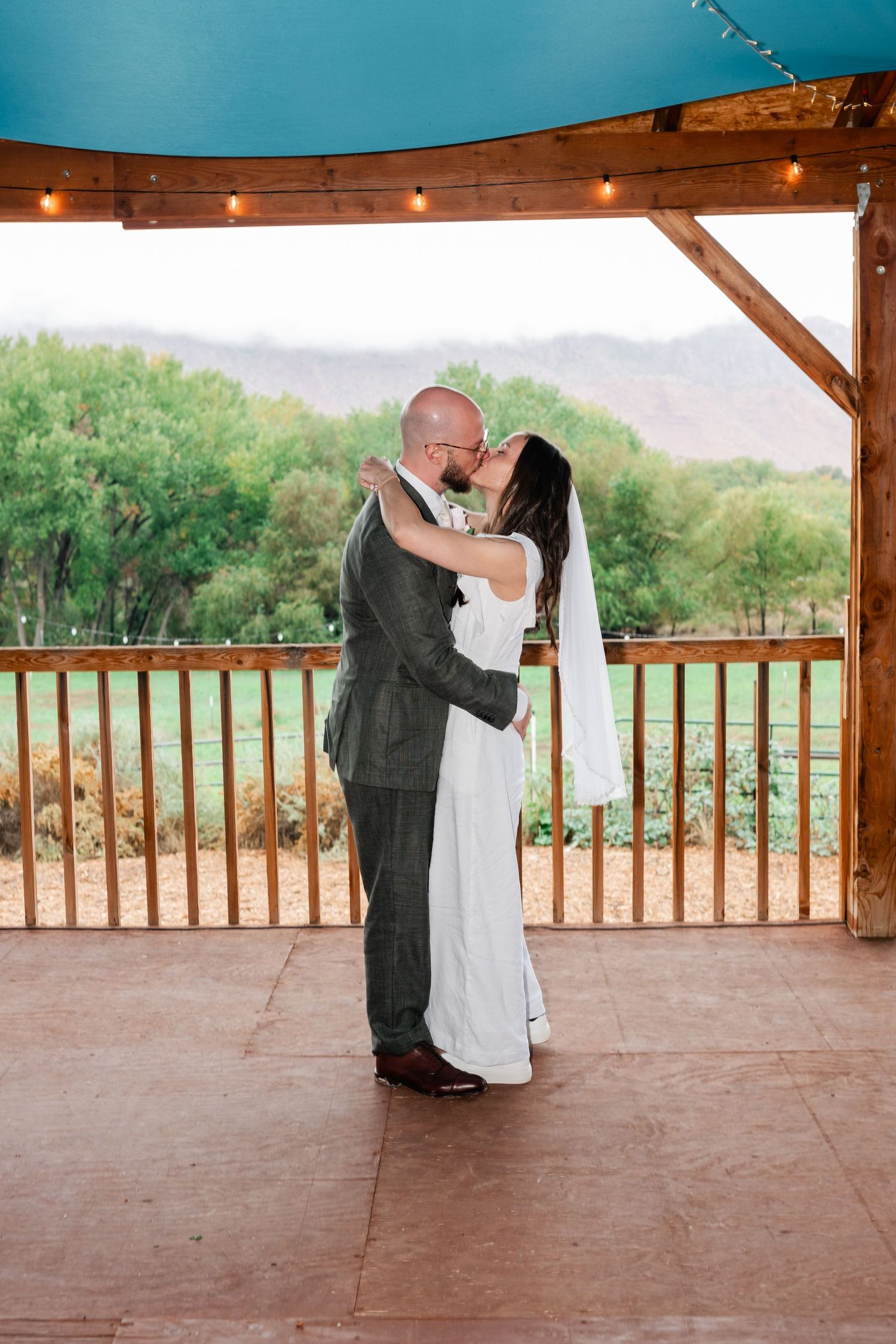 Romantic dance sequence on wooden deck with string lights and mountain views in background.