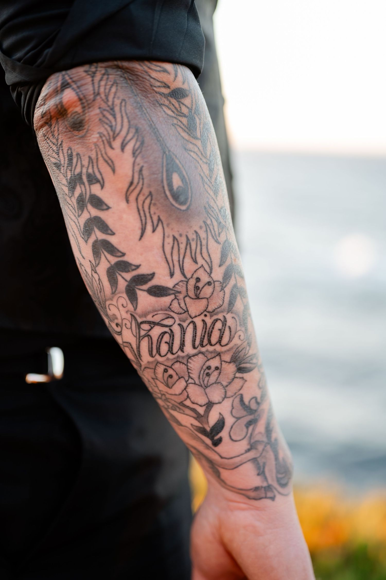Close-up view of detailed sleeve tattoo artwork on person wearing black.