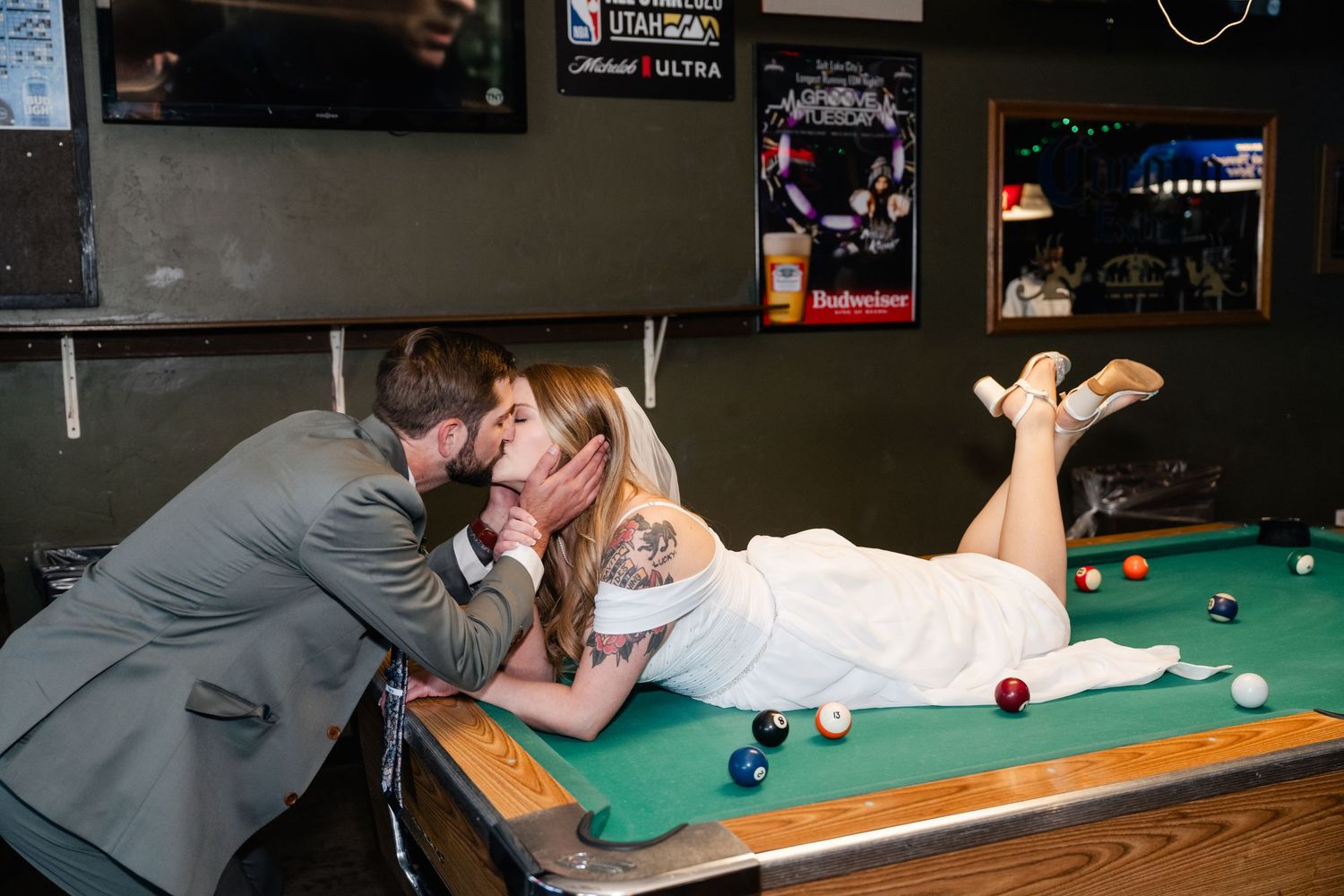 A couple shares an intimate moment while playing pool at a dimly lit bar.