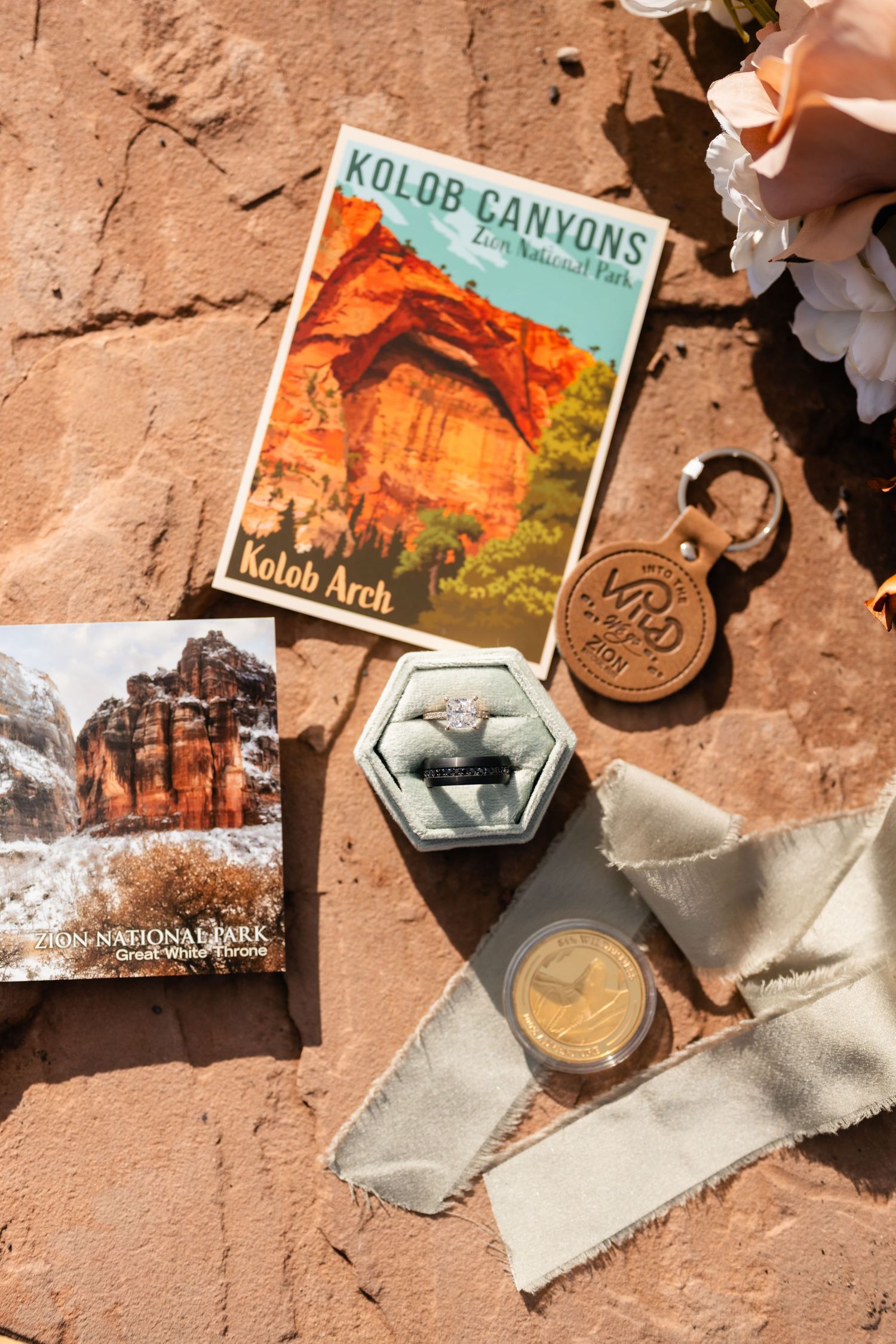 Travel postcards and memorabilia from Kolob Canyons laid out on red sandstone with decorative flowers.