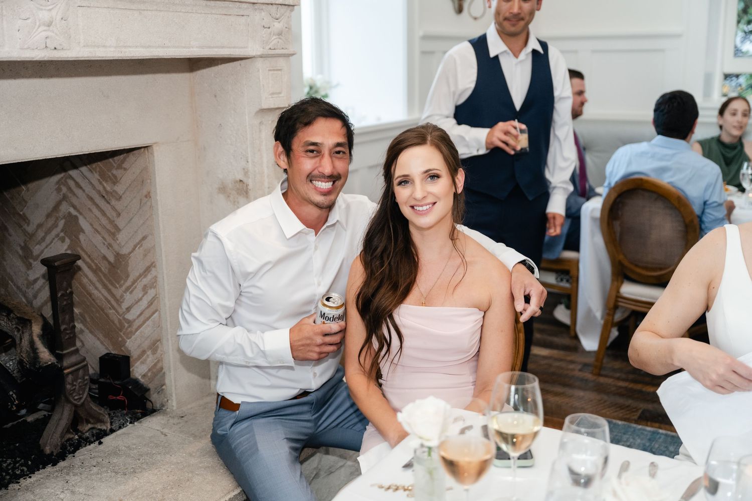 Wedding guests enjoying conversation and drinks at an elegant indoor reception.
