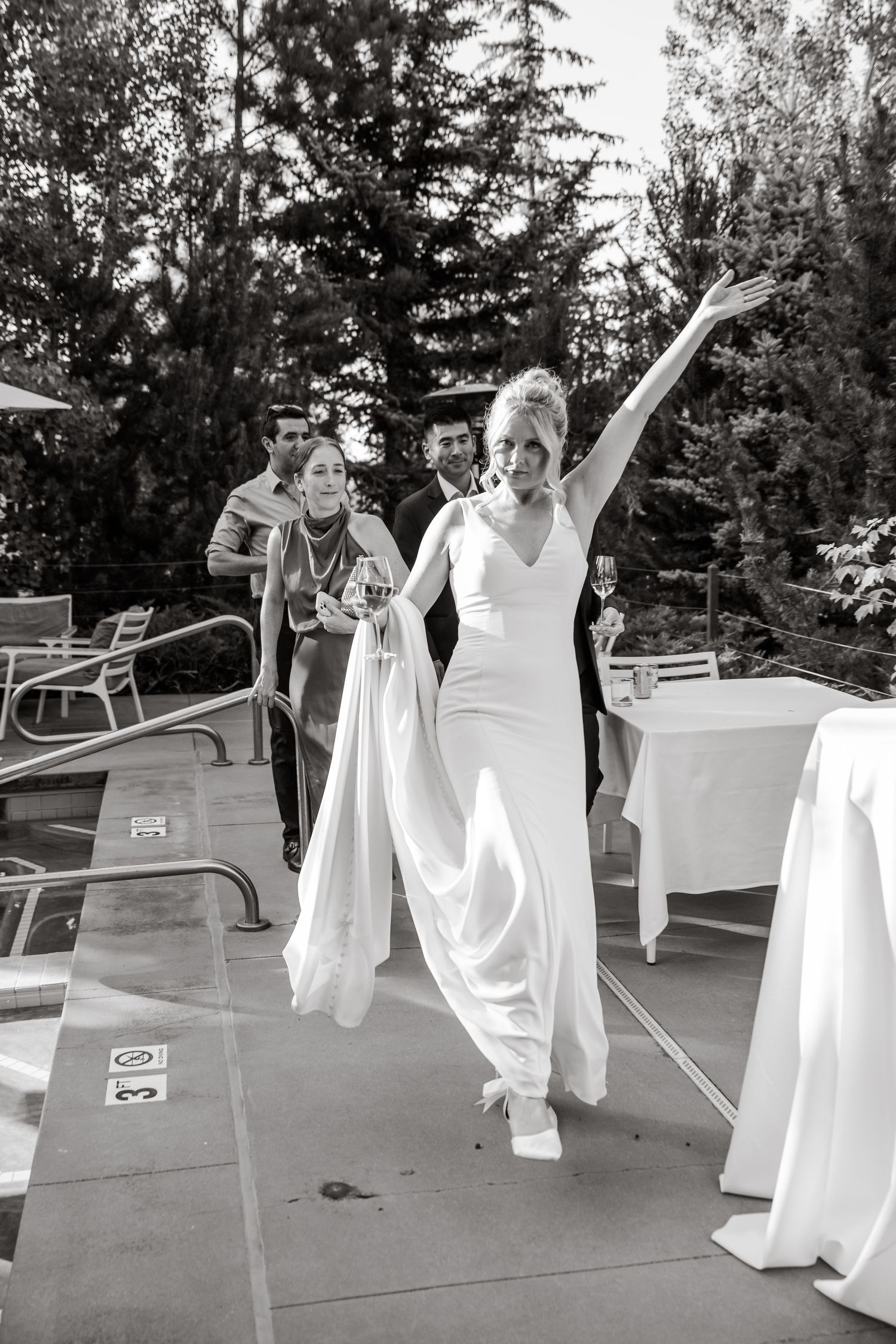 Group in white dresses dancing and celebrating outdoors in black and white photography.