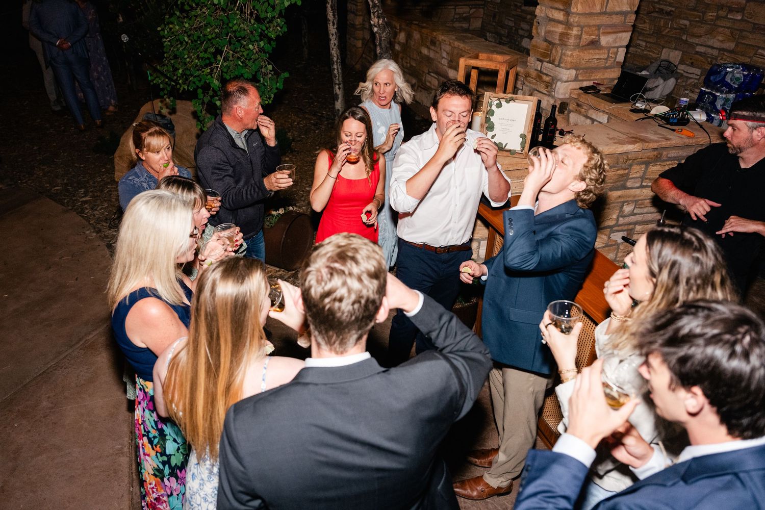 Wedding guests dancing and celebrating at an evening reception under string lights.