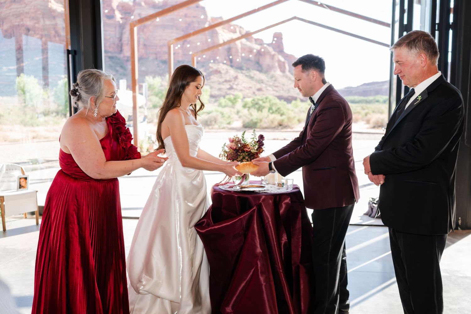 Bride and groom exchanging vows with family at an indoor desert wedding venue with red rock views.