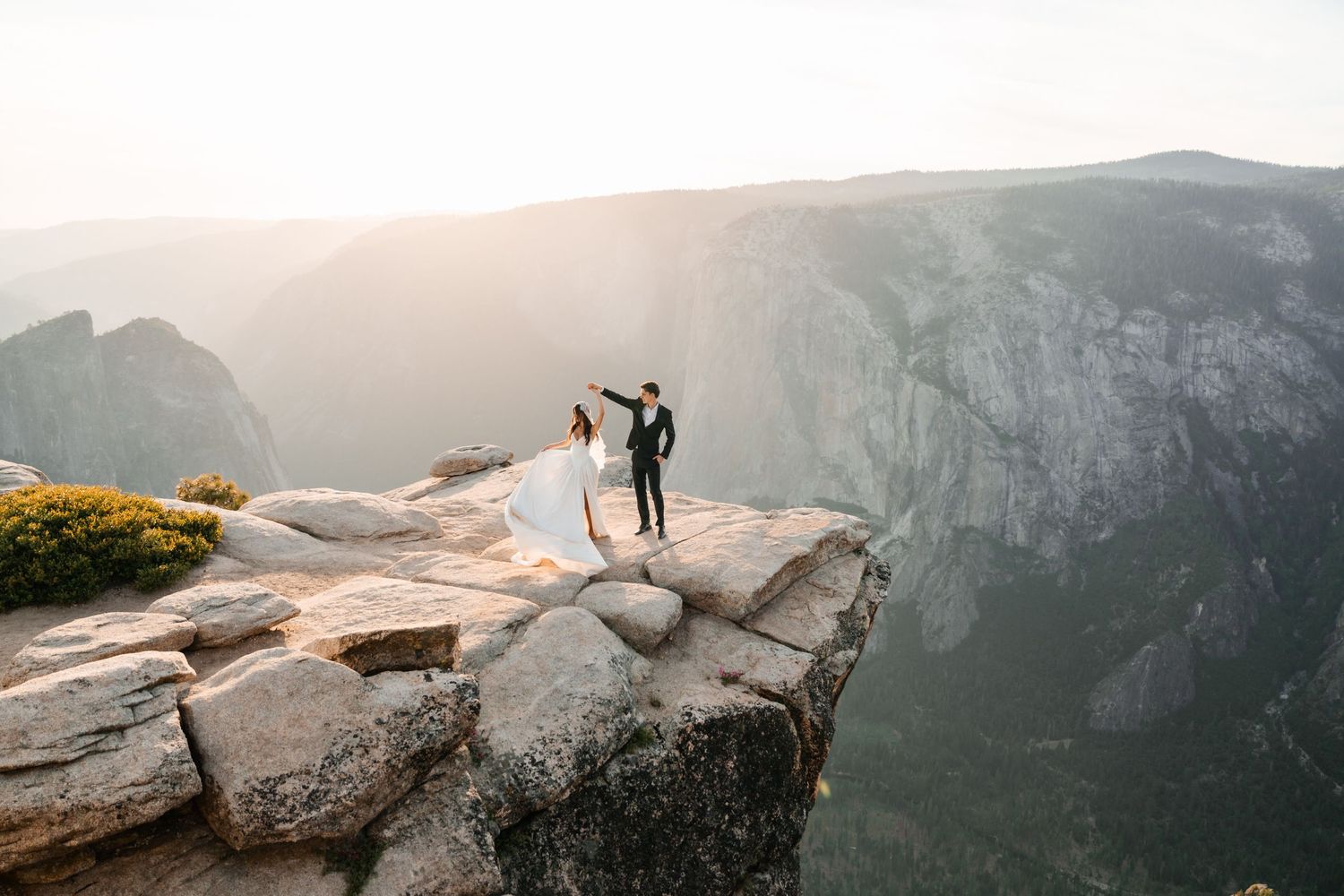Bride and groom holding hands on the edge of Taft Point cliff in Yosemite National Park.