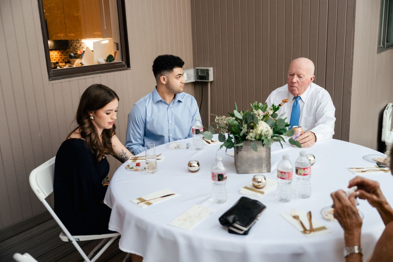 Guests seated at a round table with white linens during an indoor reception.