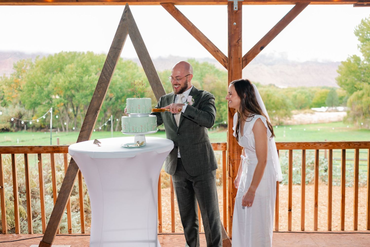 A covered outdoor deck area with wooden beams and white tables set up for an event.