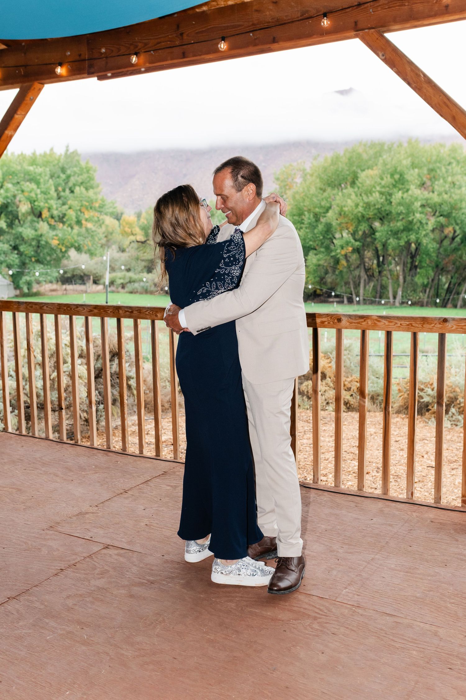 A couple sharing an intimate dance moment on a covered patio with mountain scenery.