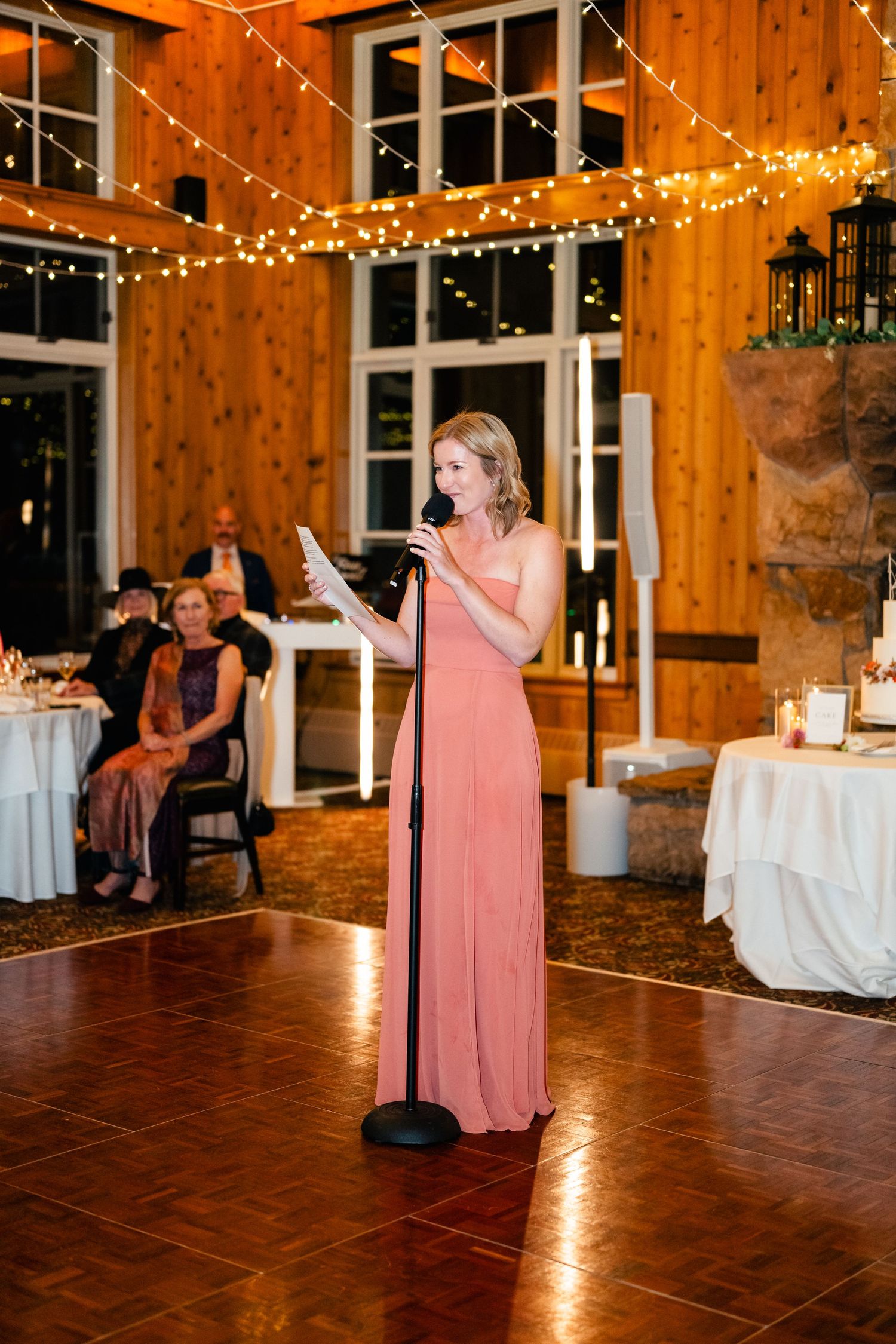 Wedding reception in rustic barn venue with string lights and wooden walls.