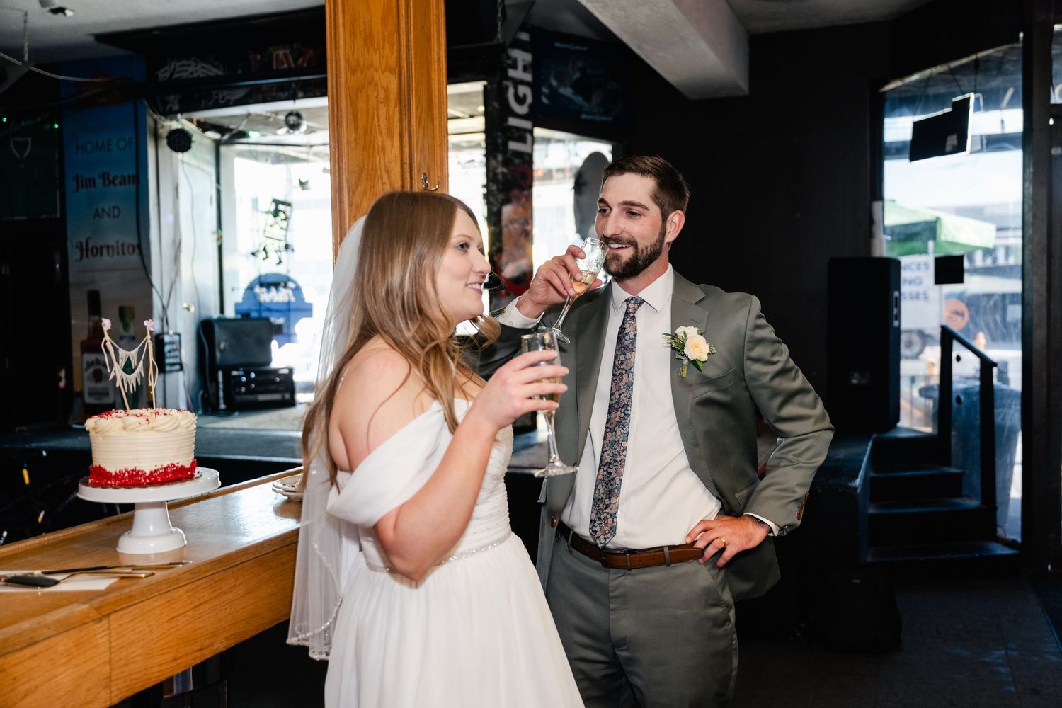 Wedding celebration scene in a dimly lit venue with people gathered around a bar area.