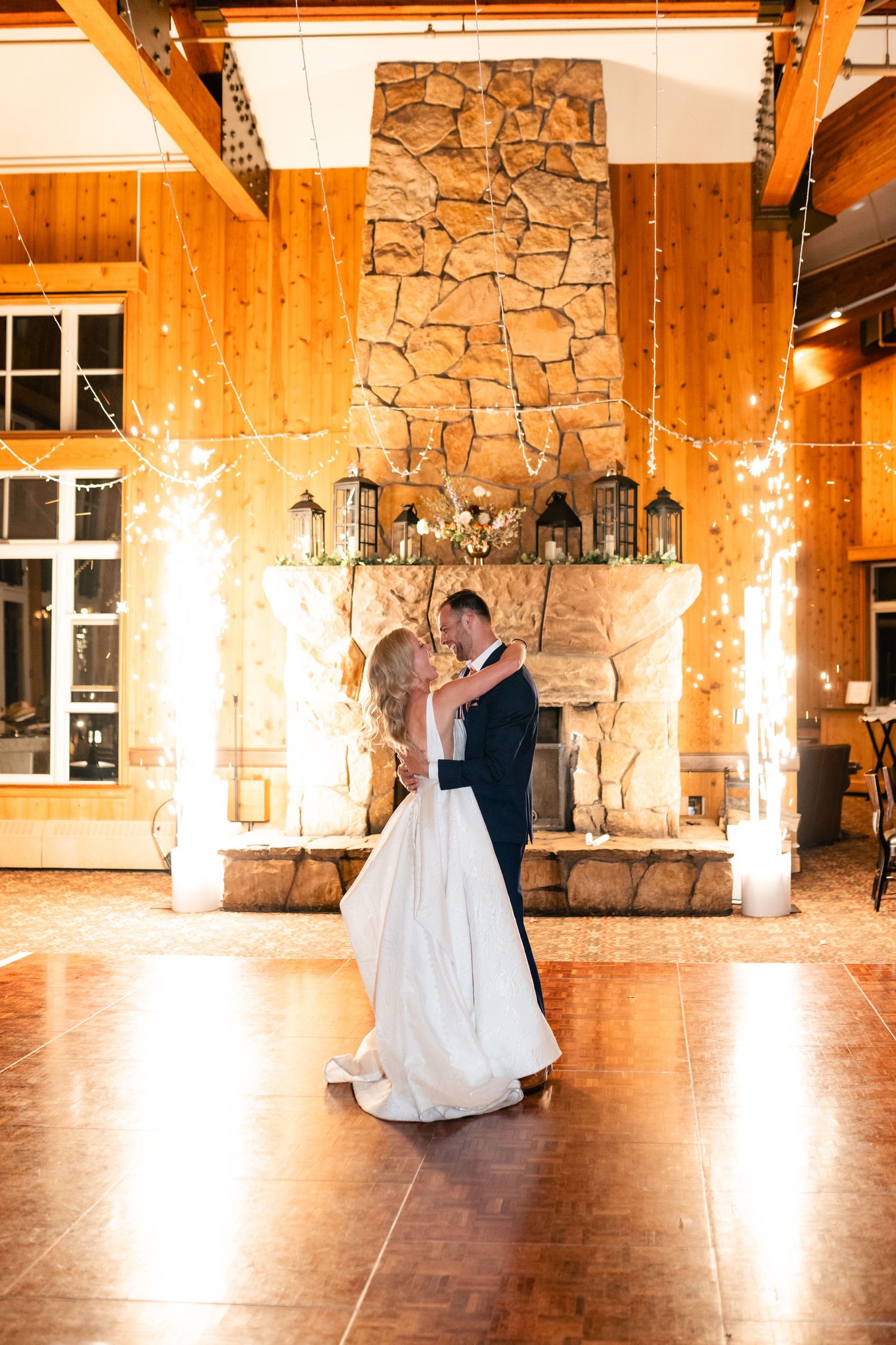 Couple's first dance in rustic stone and wood venue with dramatic lighting effects.