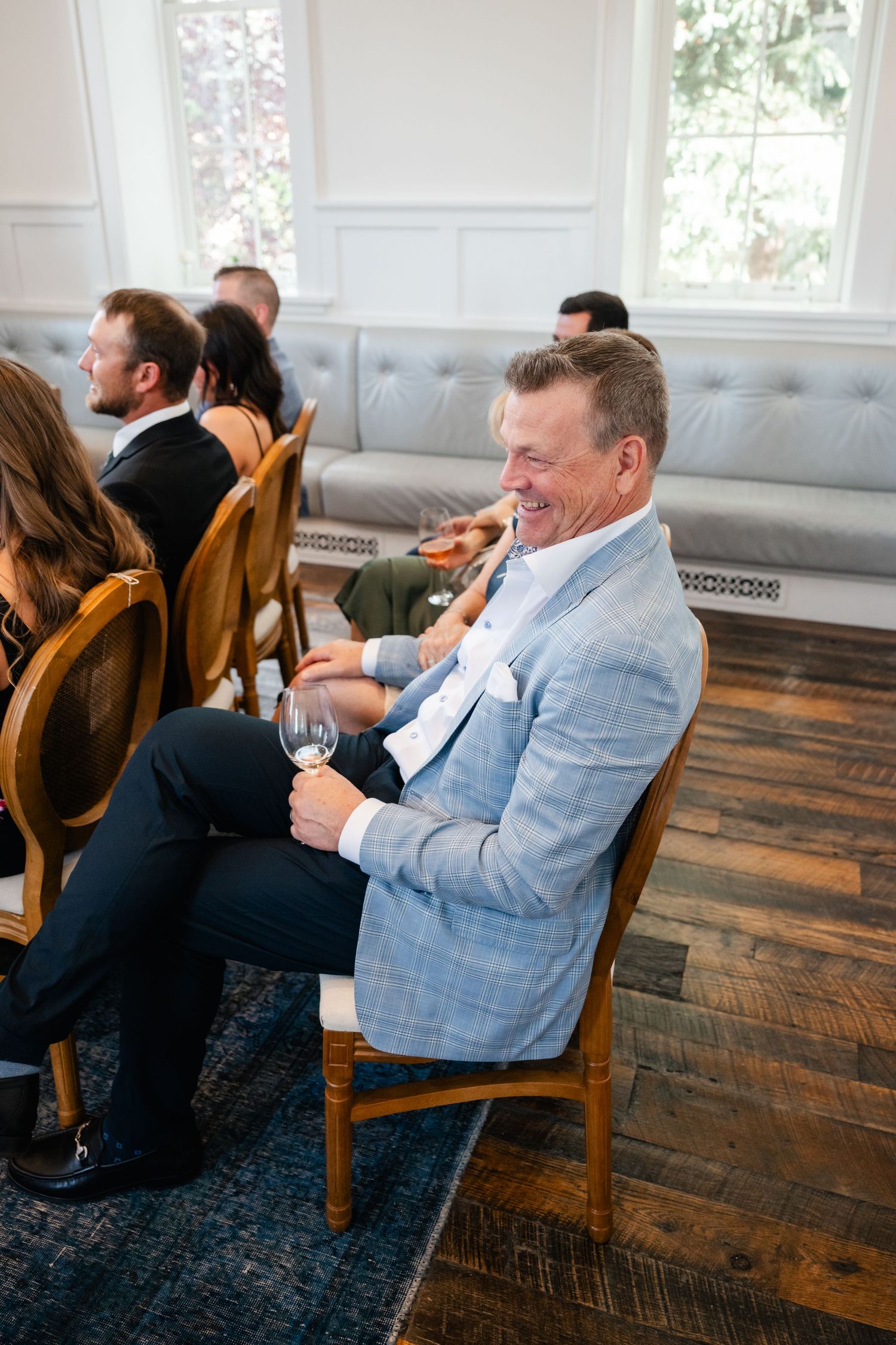 Wedding guests seated on wooden chairs enjoying the reception festivities.