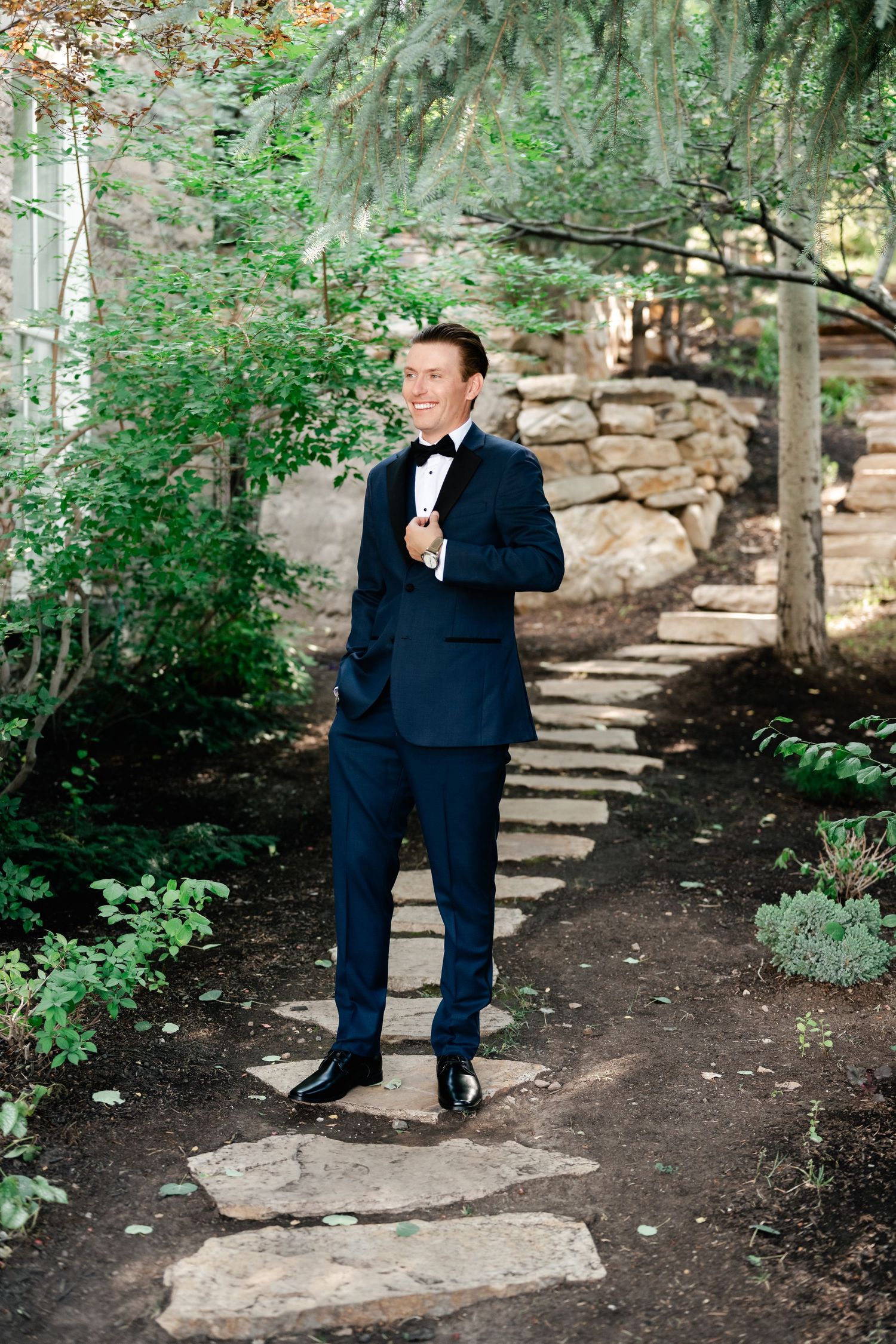 A series of five photos showing someone in a navy blue suit walking up stone garden steps surrounded by greenery.