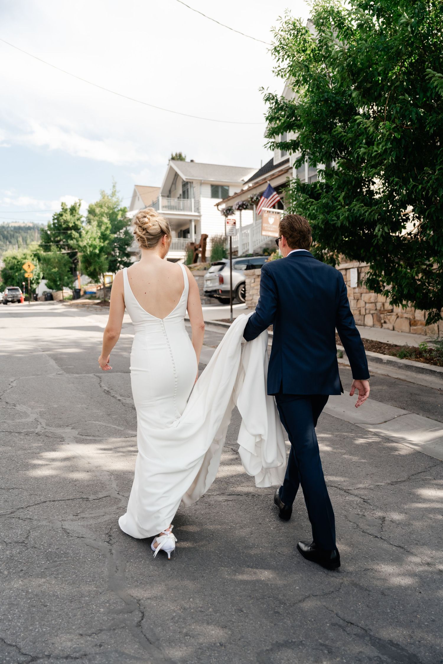 A couple strolls hand in hand down a neighborhood street after their wedding ceremony.